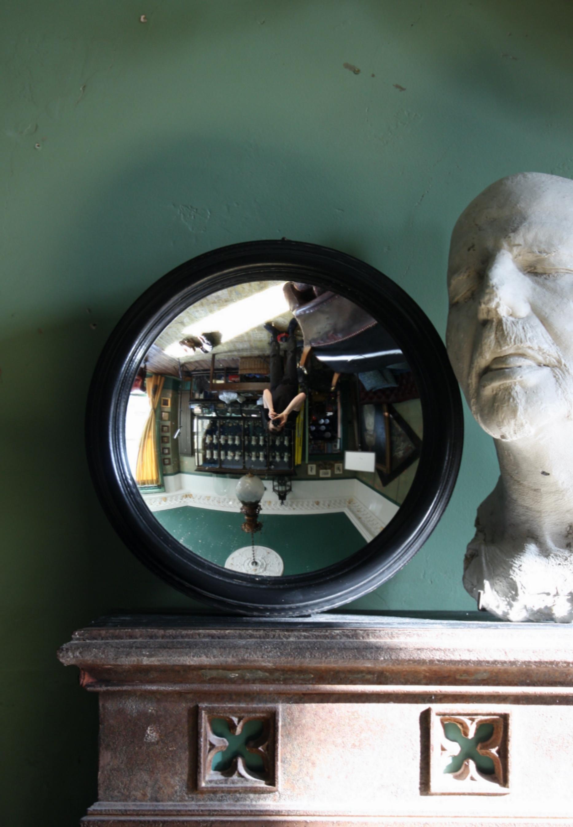 A early 20th century concave mirror plate, housed in a later decorative Regency style ebonized frame.

The mirror has some minor pitting to the plate, the surface is scratch and abrasion free 

A elderly spilt in the frame, the mirror also has a