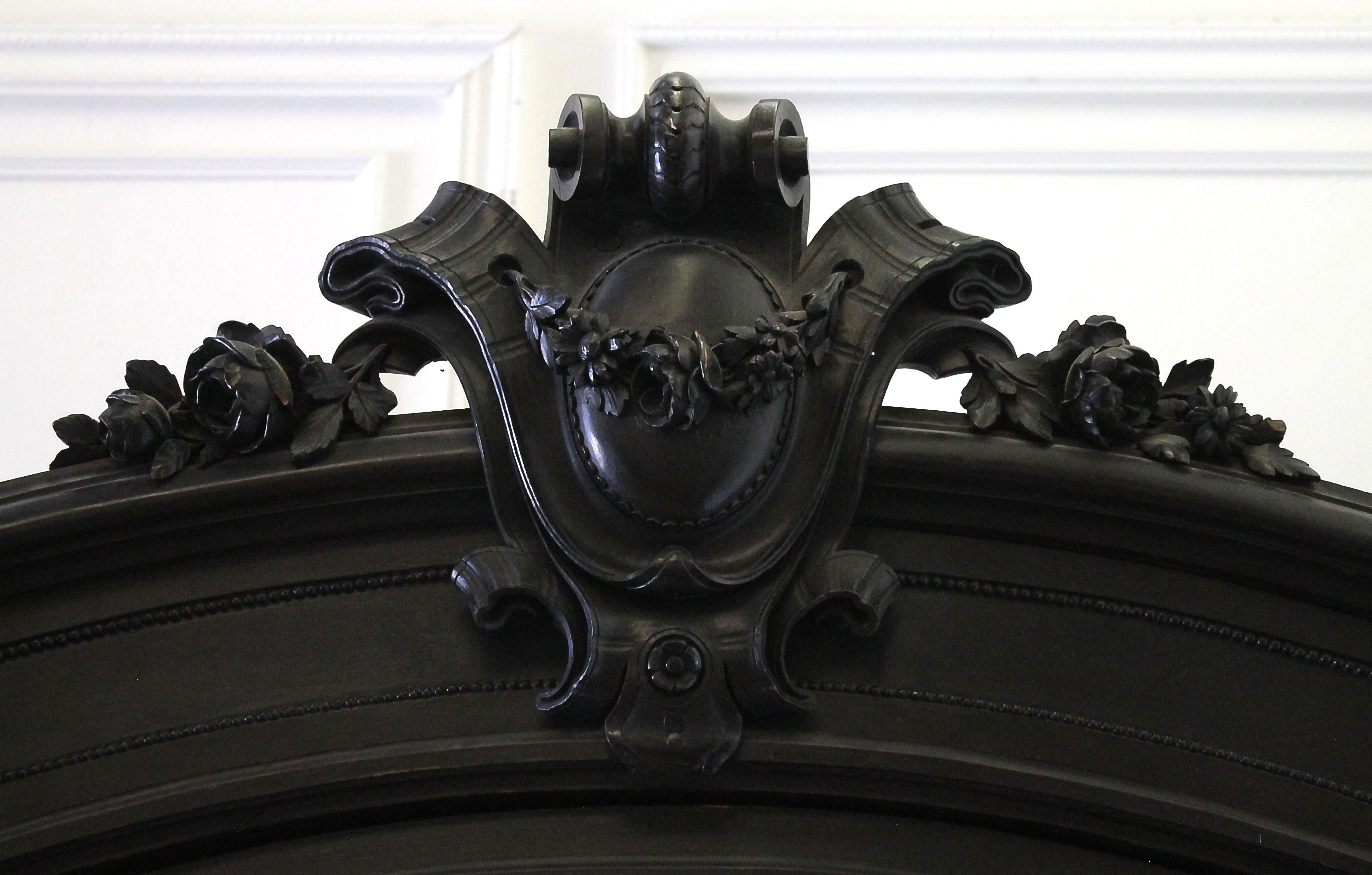 Ebonized Empire French Louis XVI style armoire.
Beautiful single door armoire, with large carved medallion, rose swag, with fluted columns, and large carved finials. Door has original mirror, subtle antique patina to the mirror. 1