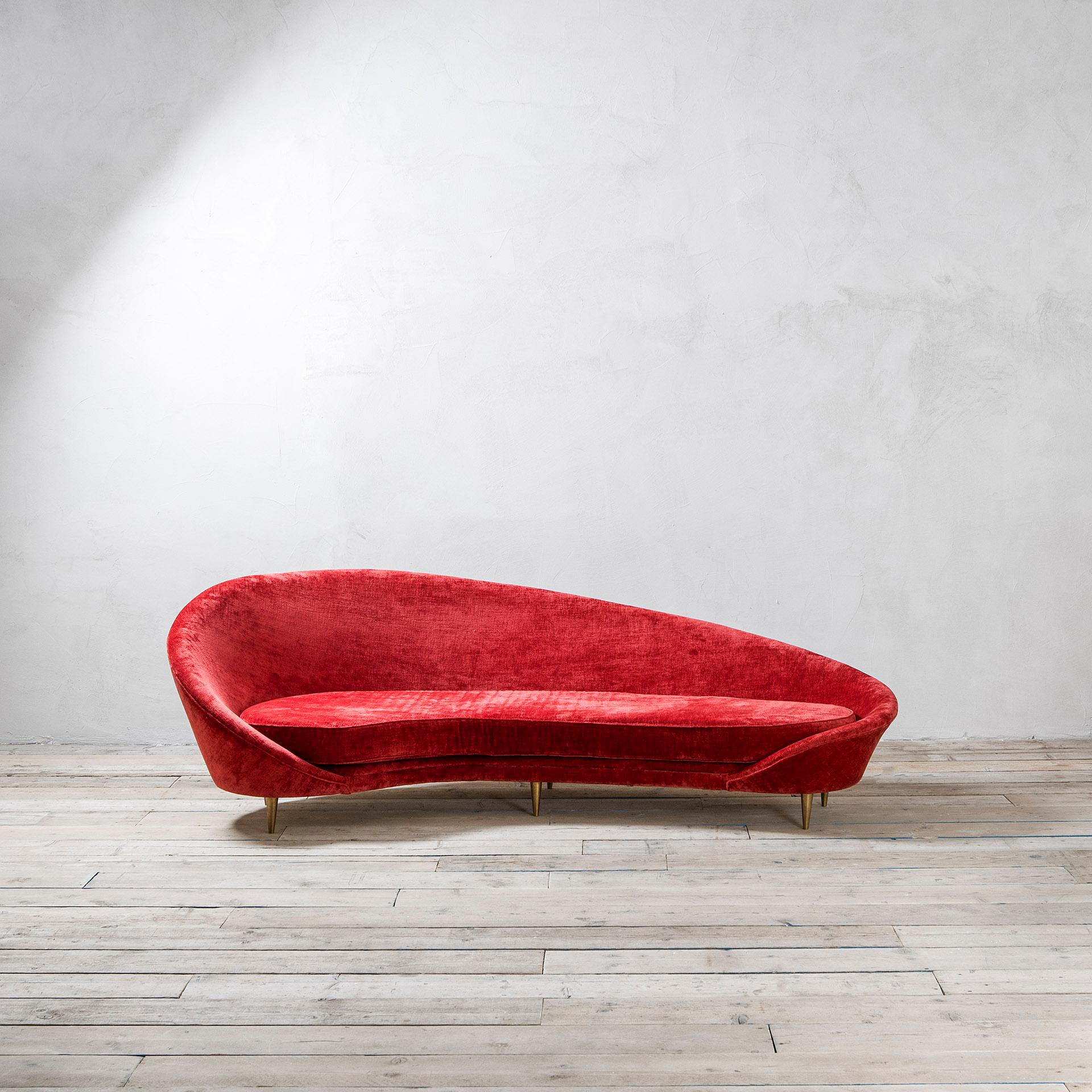 Virgola sofa is inspired by Federico Munari's sofa from the 50s. 
The 6 feet are in full brass, shaped as truncated cone. The main characteristic of this sofa is the fabric: a whole piece of red velvet, a very precious kind of velvet which allows