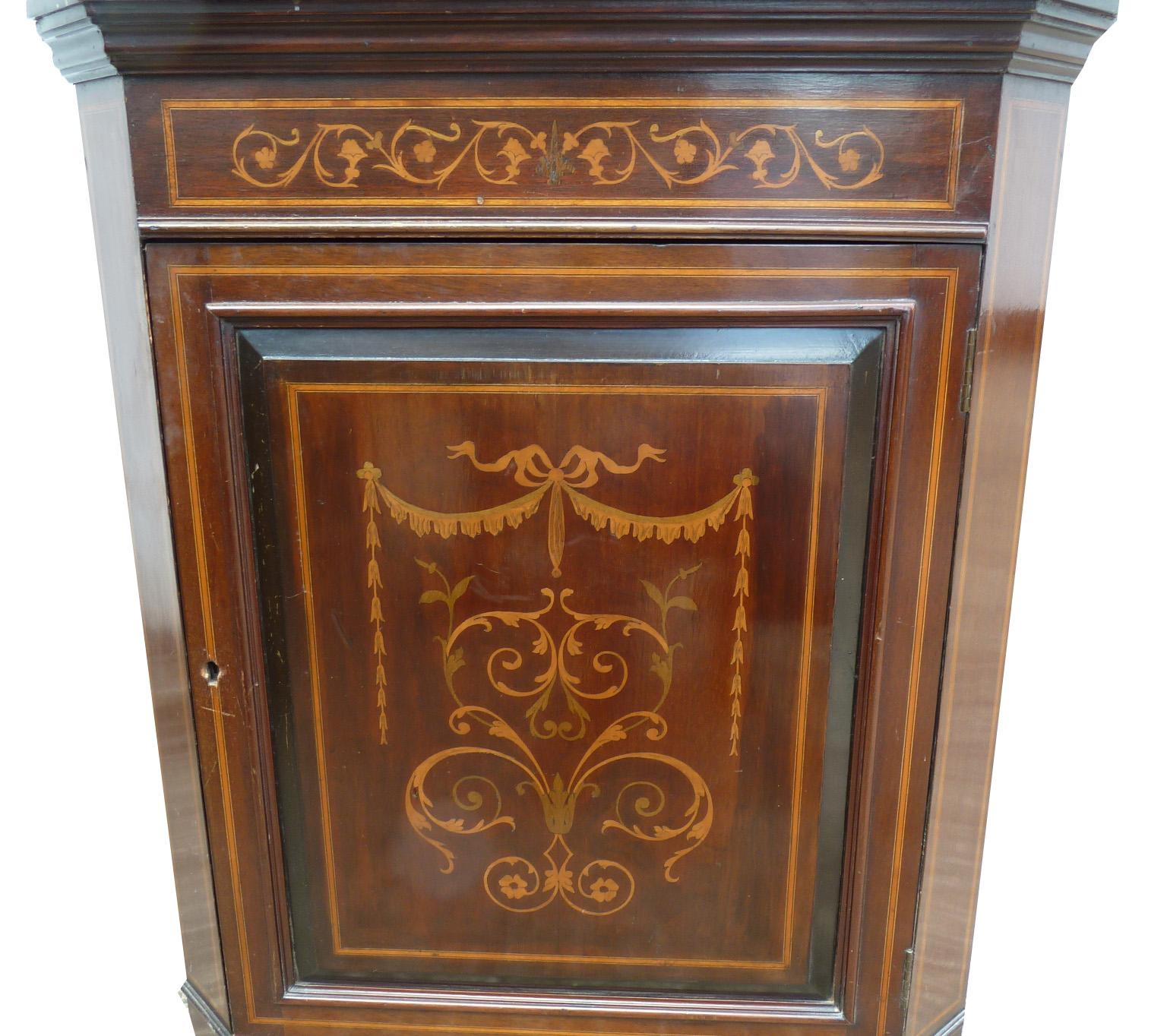 For sale is an Edwardian marquetry inlaid corner display cabinet. The top of the cabinet has an inlaid broken arch pediment above a single glazed door. Below this is a marquetry inlaid door. This piece is in good condition, with average wear
