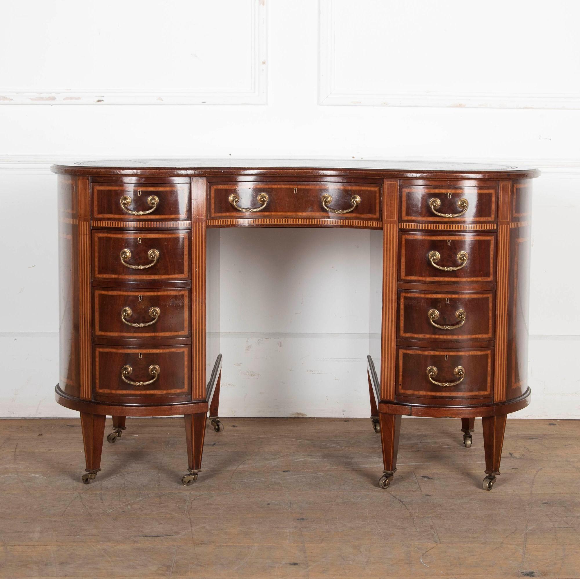 Very good quality early 20th century mahogany and inlaid writing desk. 
English, circa 1900 with original brass handles, castors, and leather inserts. Having nine mahogany lined drawers, this a very practical neat sized desk and would also make for