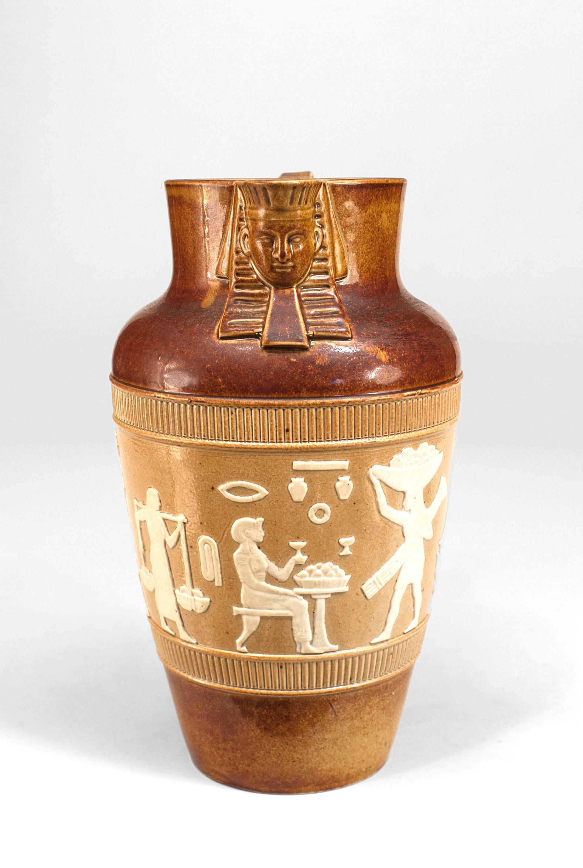 Middle Eastern Egyptian-style (English 1920s) large brown pitcher with sphinx head spout and beige and white classical figures in relief (impressed: DAULTON, LAMBBETH).
 