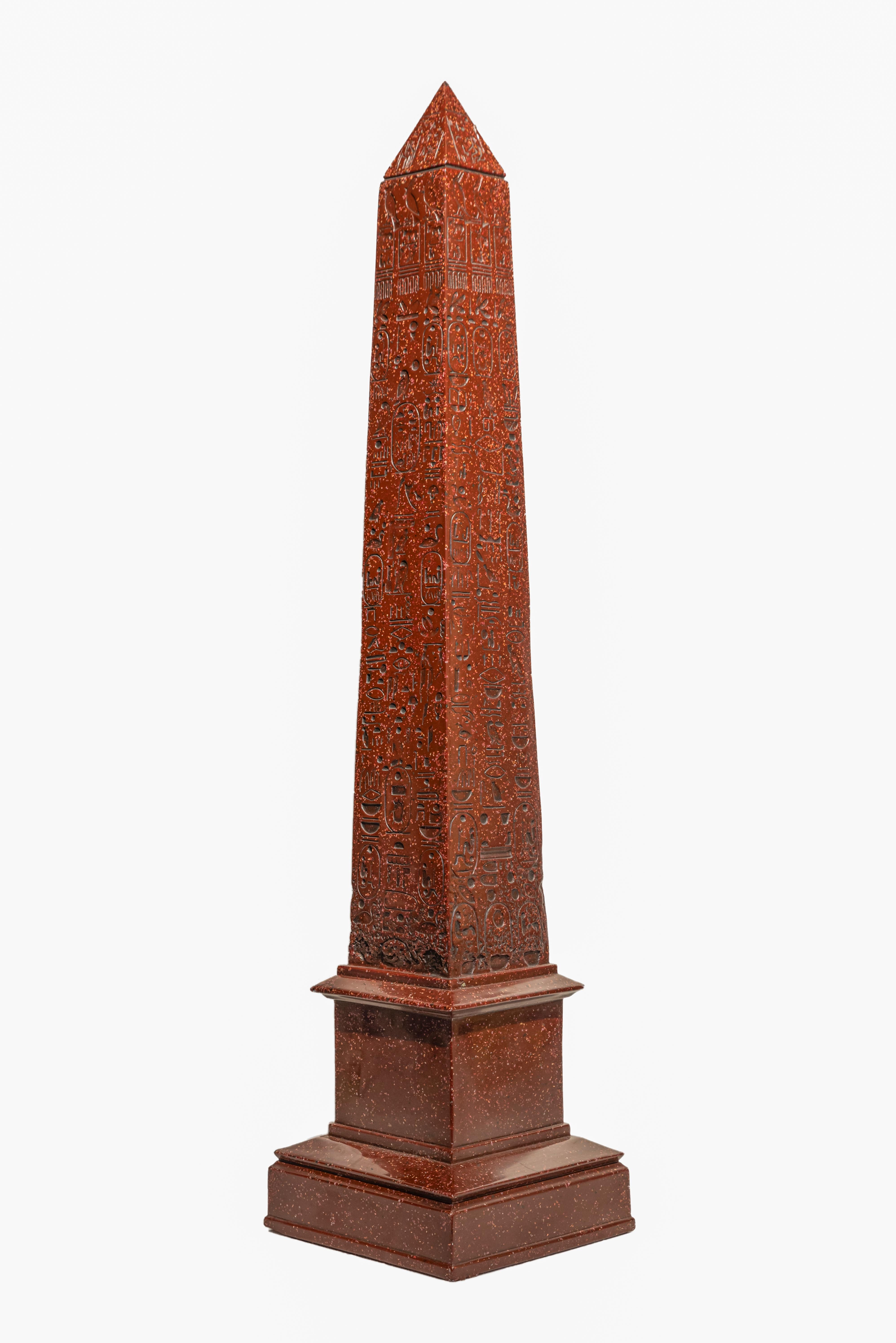 Egyptian Revival  faux marbre obelisk.
Classic model adorned by hand carved egyptian hieroglyphics.
Made in resin pate as faux red marble or porphyry.