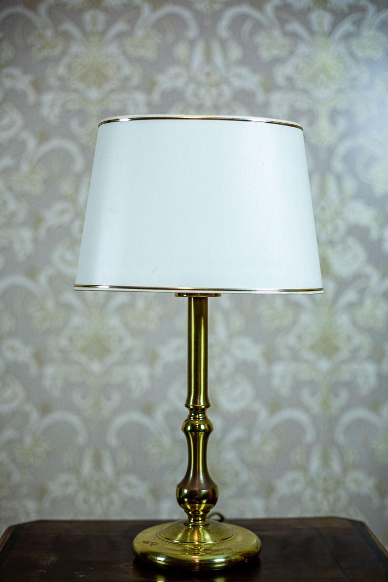 We present you a small modern lamp with an oval lamp shade.
The base is made of metal in the color of gold.

There is a socket for one E 27 light bulb.

The power source is 230 V.

This lamp is in good condition. The golden layer is worn off