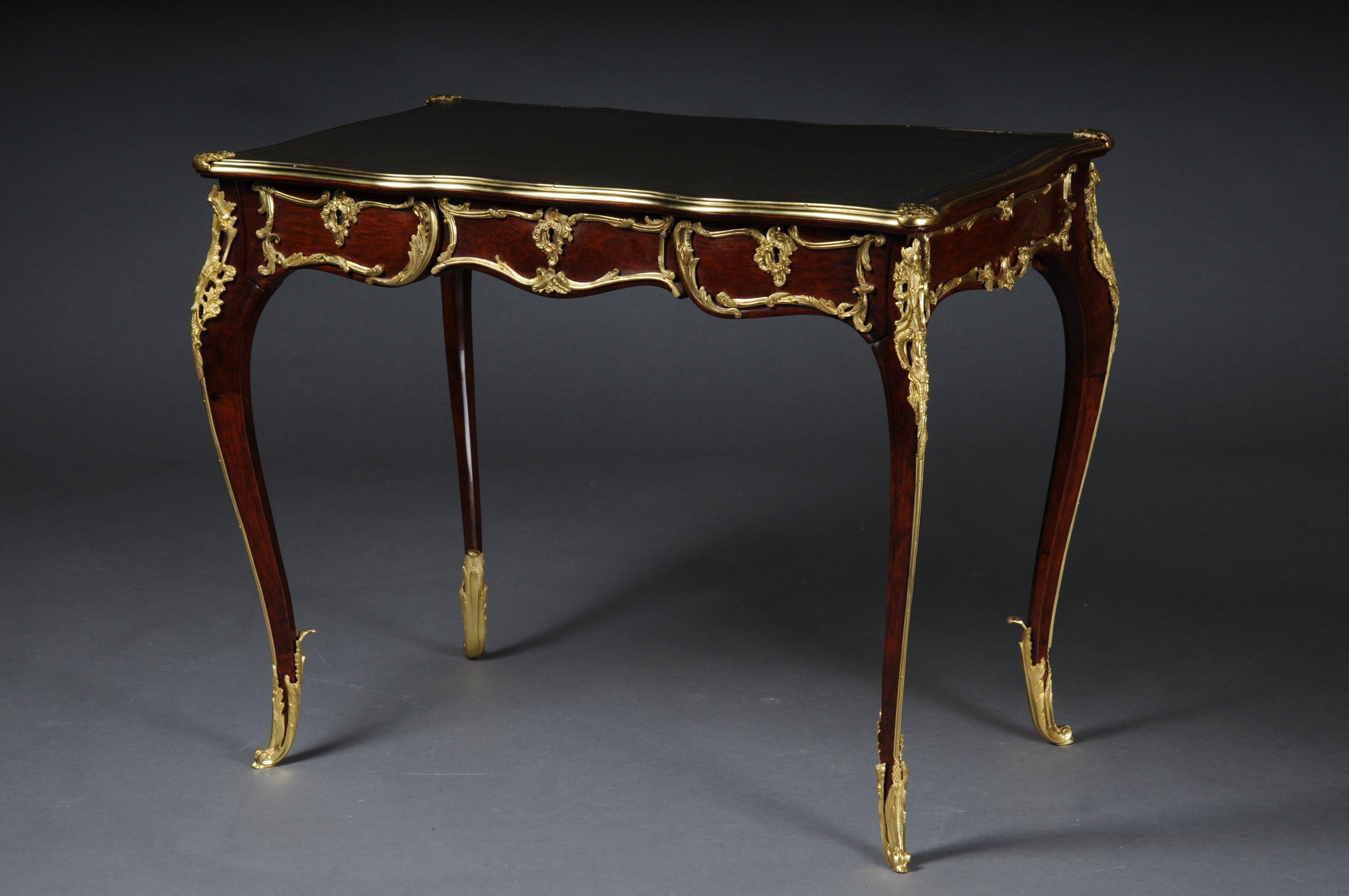 Elegant veneered bureau plat / desk in Louis XV style

Solid beech wood and veneer. Very fine, floral bronze fittings.
Curved and pronounced / arched wooden body. Frame base with four-sided curvature.
3 drawers and wide knee compartment ending