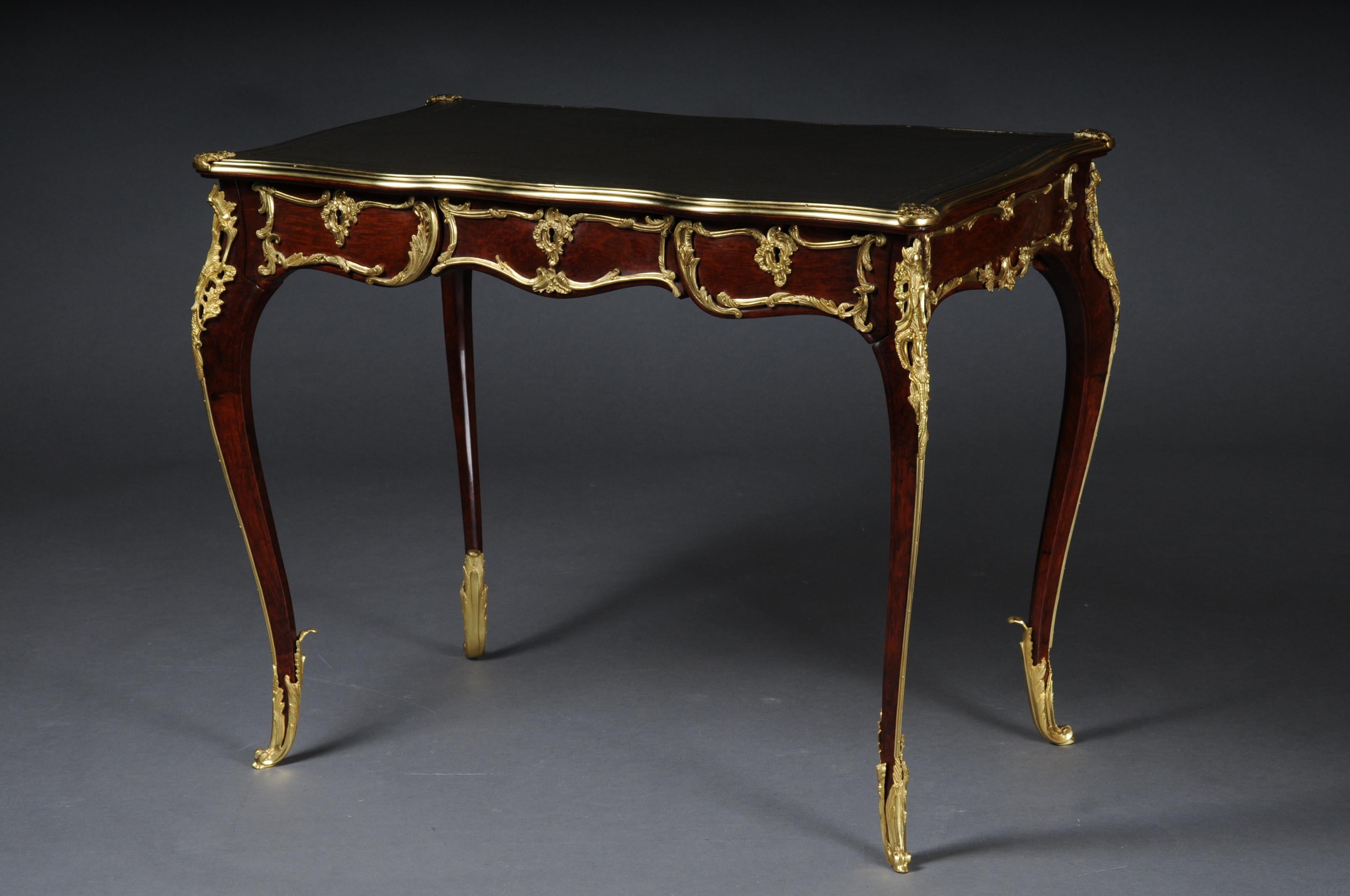 Elegant veneered bureau plat or desk in Louis XV style

Solid beechwood and veneer. Very fine, floral bronze fittings.
Curved and pronounced or arched wooden body. Frame base with four-sided curvature.
3 drawers and wide knee compartment ending