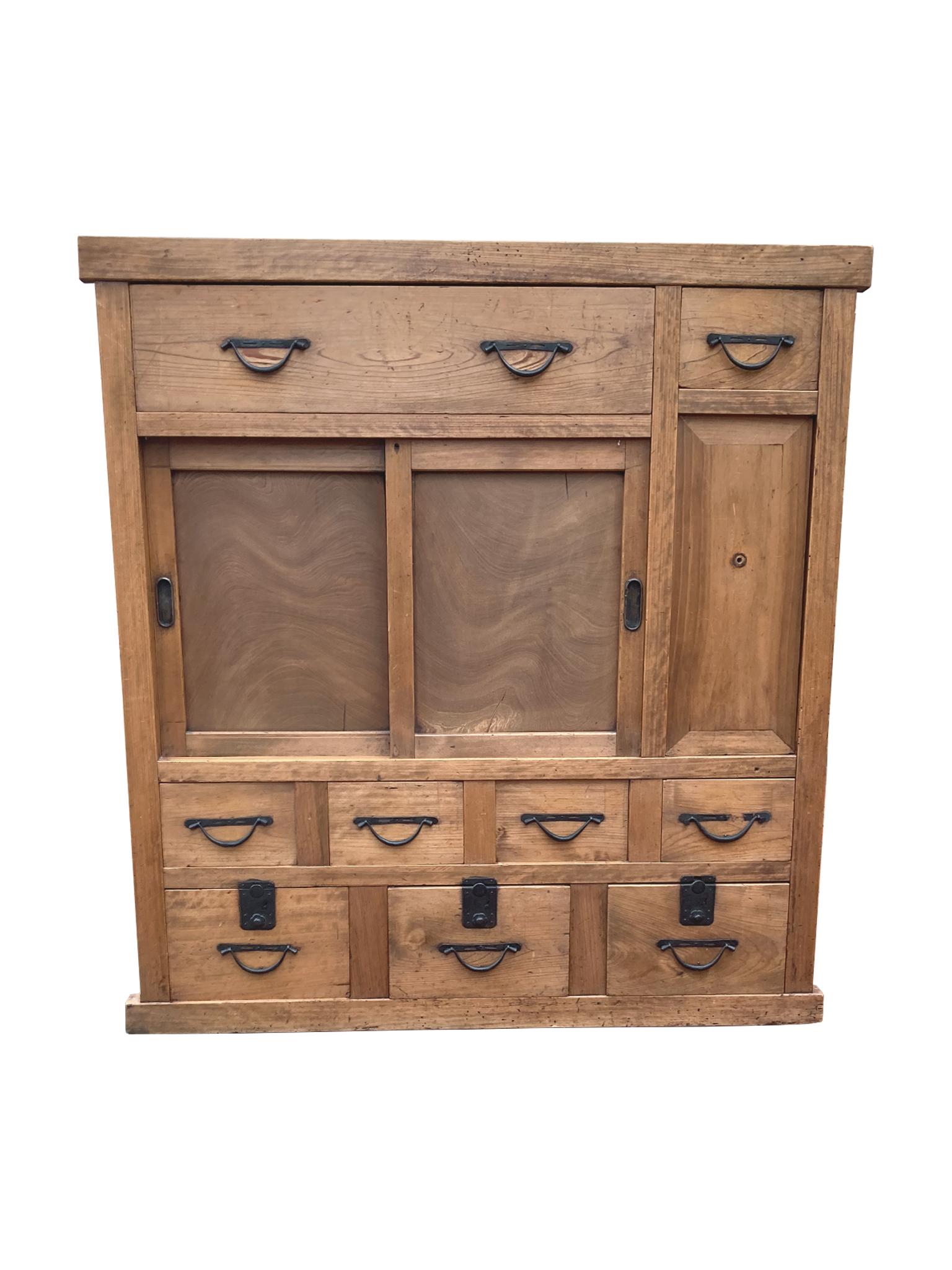 Japanese tansu chest, handcrafted circa first half of the 20th century. The tansu is elmwood with hand-forged iron hardware. It is an ideal storage space, constructed with multiple compartments, including 9 drawers and 2 cabinets. We love the