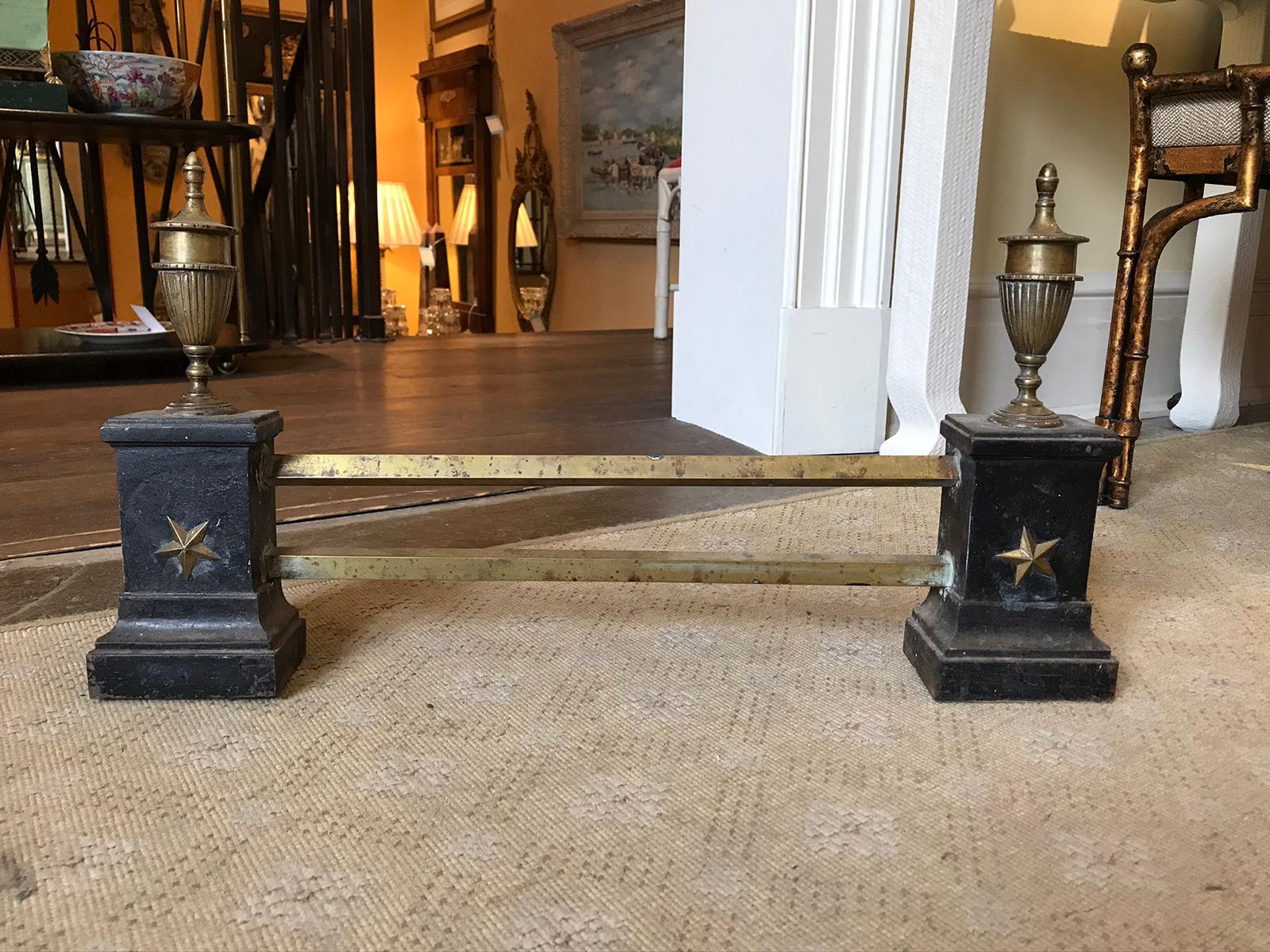 20th century Empire style brass fireplace fender with urn finial and star detail.