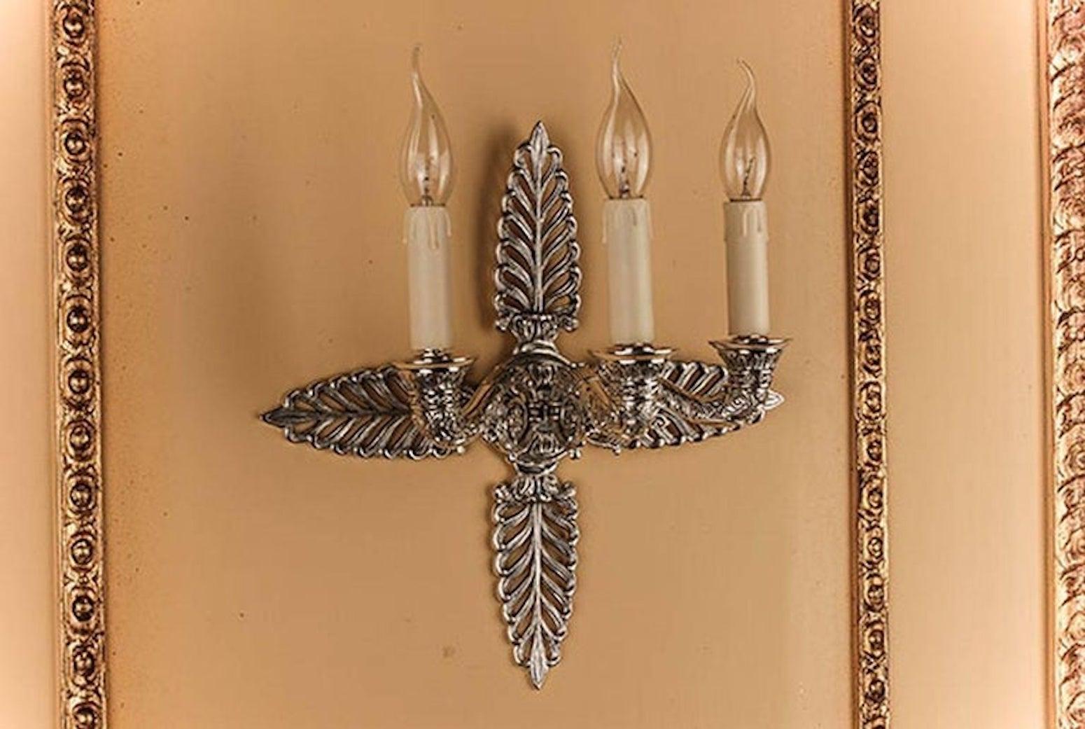 Aplique decorativo de estilo Imperio de 1800.
Fundición fina, bronce plateado. Tres estilizados brazos de luz en forma de cuerno.