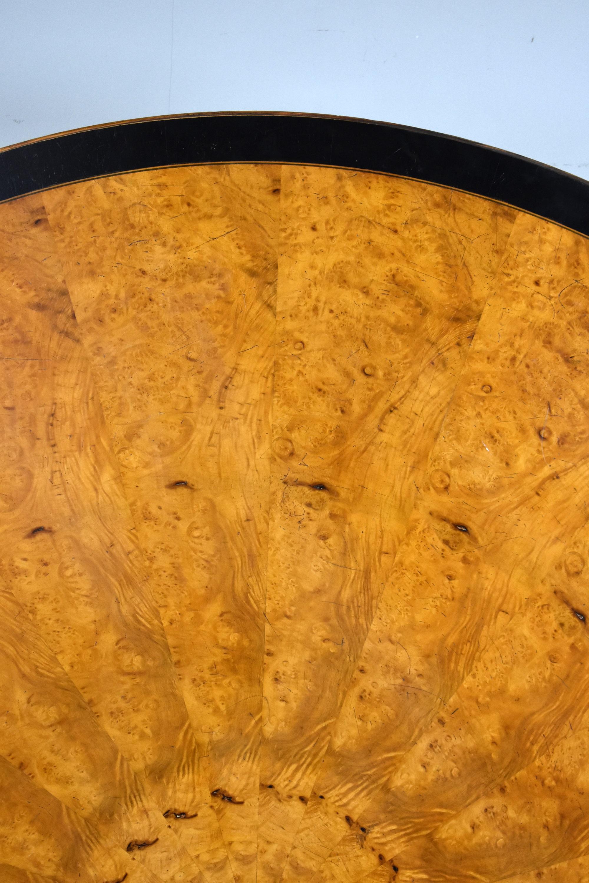 For sale is a very good quality large circular burr walnut dining table. The top having an ebony banded edge with superb radial burr walnut veneers surrounding the ebonised centre, above a turned column with four scrolled legs. This table is in good