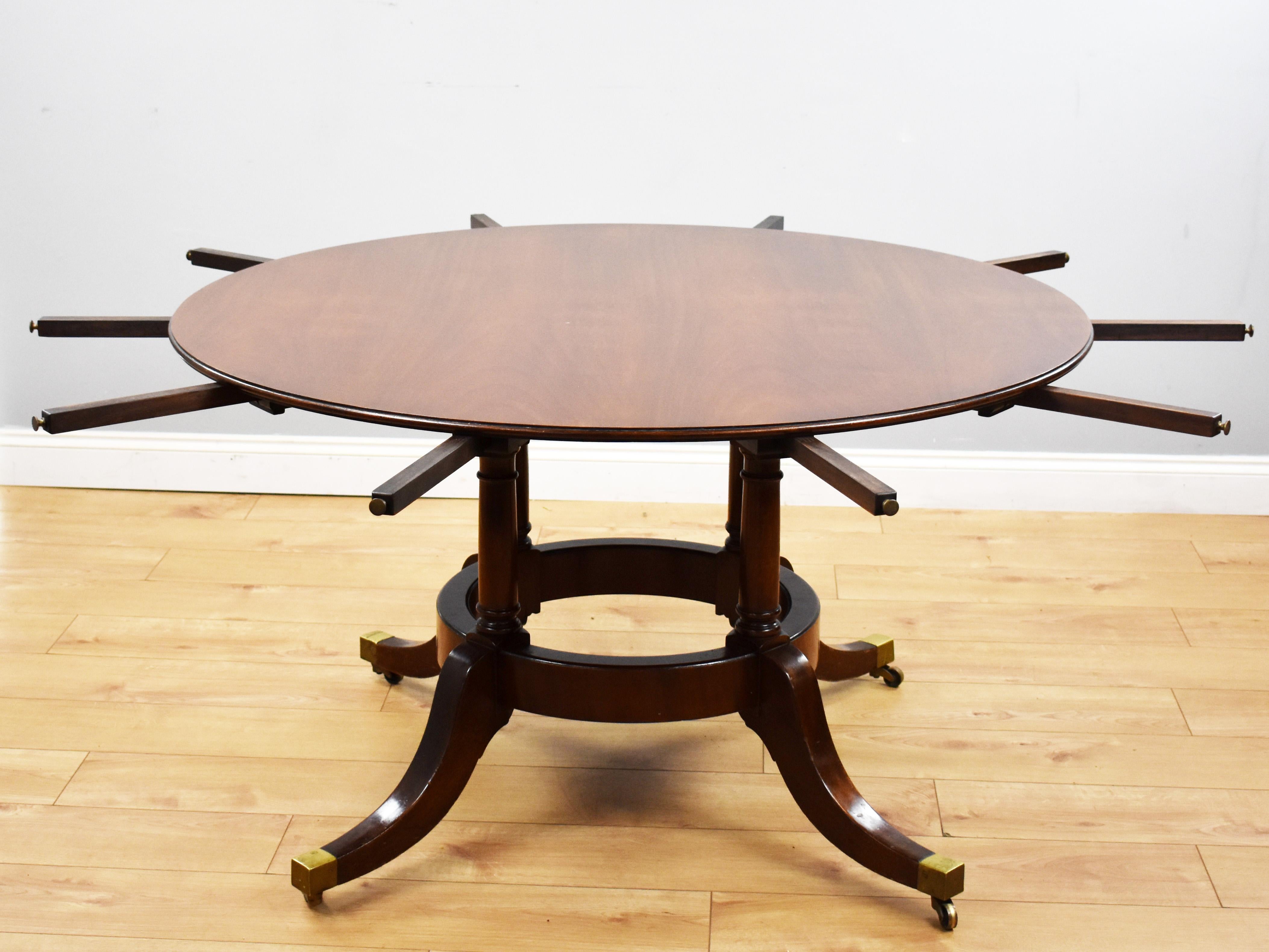 For sale is a good quality large mahogany circular extending dining table. The circular top, with five additional leaves, above four columns united by a circular stretcher raised on out swept legs terminating on brass castors. The table comes
