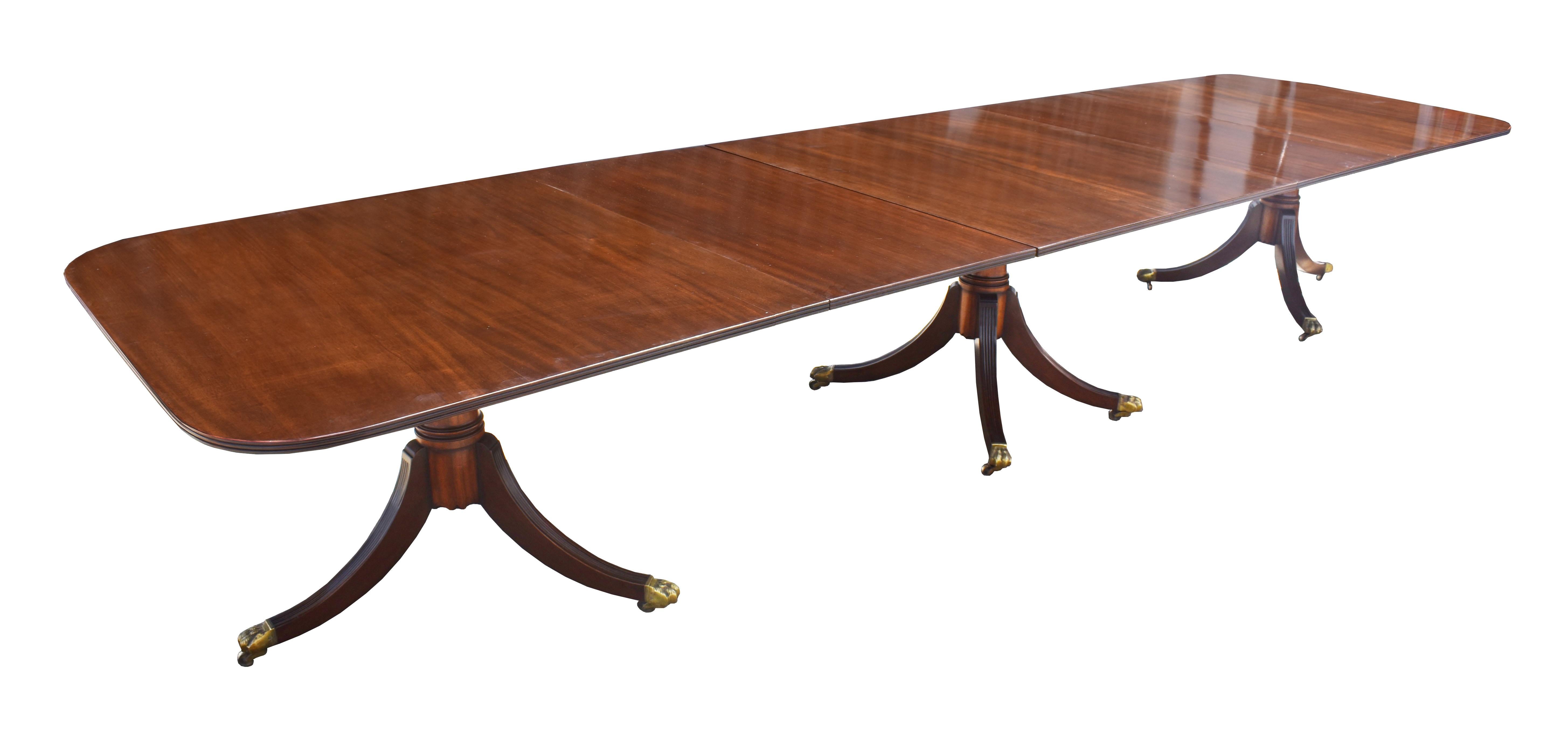 For sale is a good quality antique Regency style solid mahogany pedestal dining table, complete with two additional leaves, the table stands on three turned pedestals, with splayed legs terminating on brass lions paw castors. The table is in very