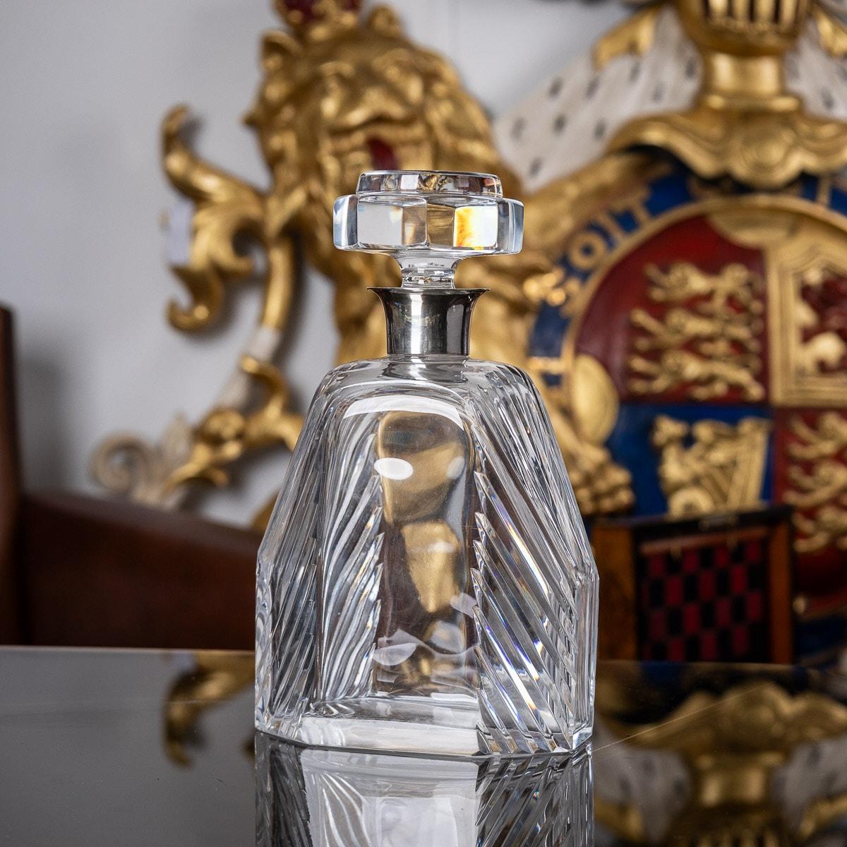 Antique early 20th century English Art Deco solid silver and glass large decanter. Of particularly large size with diagonally cut crystal glass body and mounted with elegant octagonal stopper. Applied with a stylized silver collar. This large