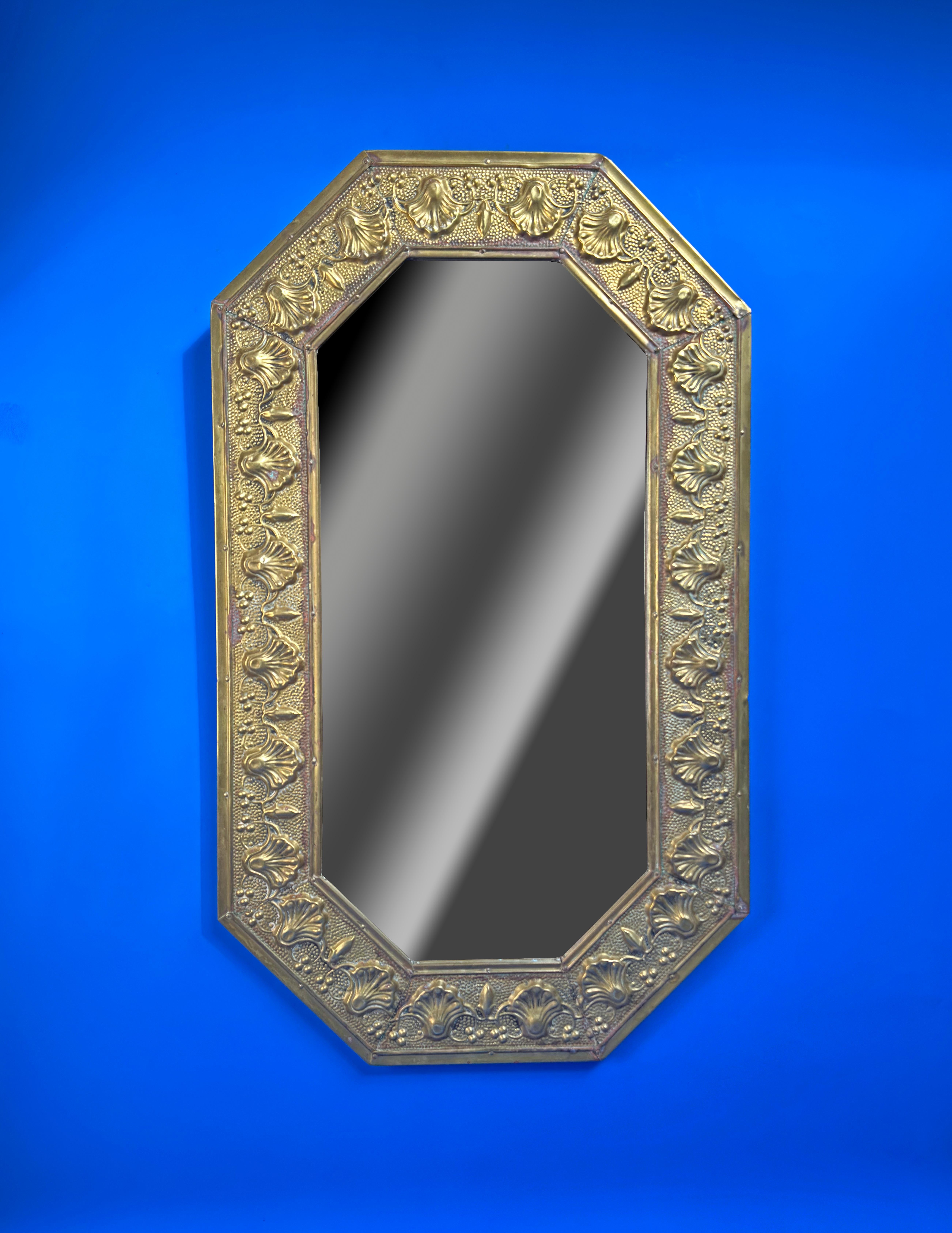 A beautiful arts and crafts mirror made in England around the 1920s. 

The octagonal mirror was created from sheet brass and then hammered using the repousse technique to create the decorative frame border. 

The mirror has been mounted on a