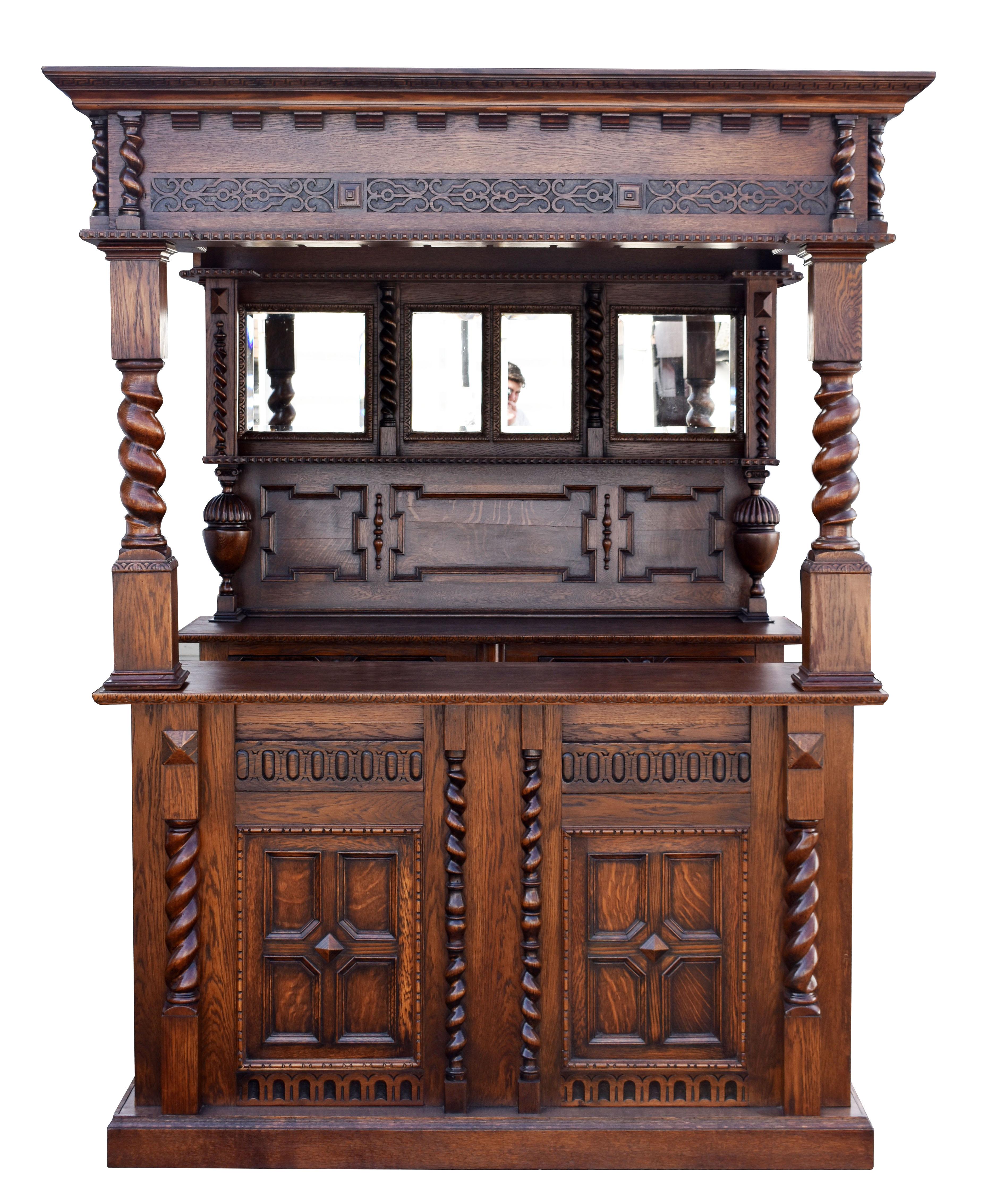 For sale is an early 20th century Jacobean style carved oak front and back bar. The canopy, having nicely turned barley twist columns to the corners and a carved panel in the centre, also features a leaded glass panel in the ceiling. This is