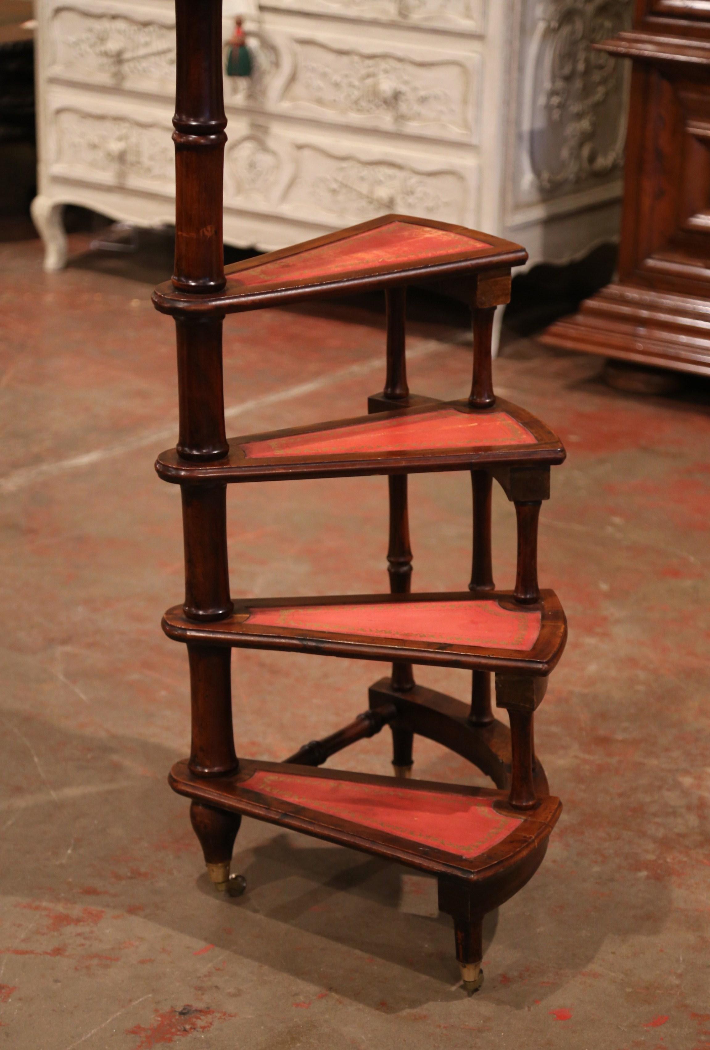 Created in England circa 1980 and standing on four turned legs with bottom wheels, the tall circular step ladder features four stairs rolled around a turned, central post embellished with a decorative brass finial at the pediment. Each step is