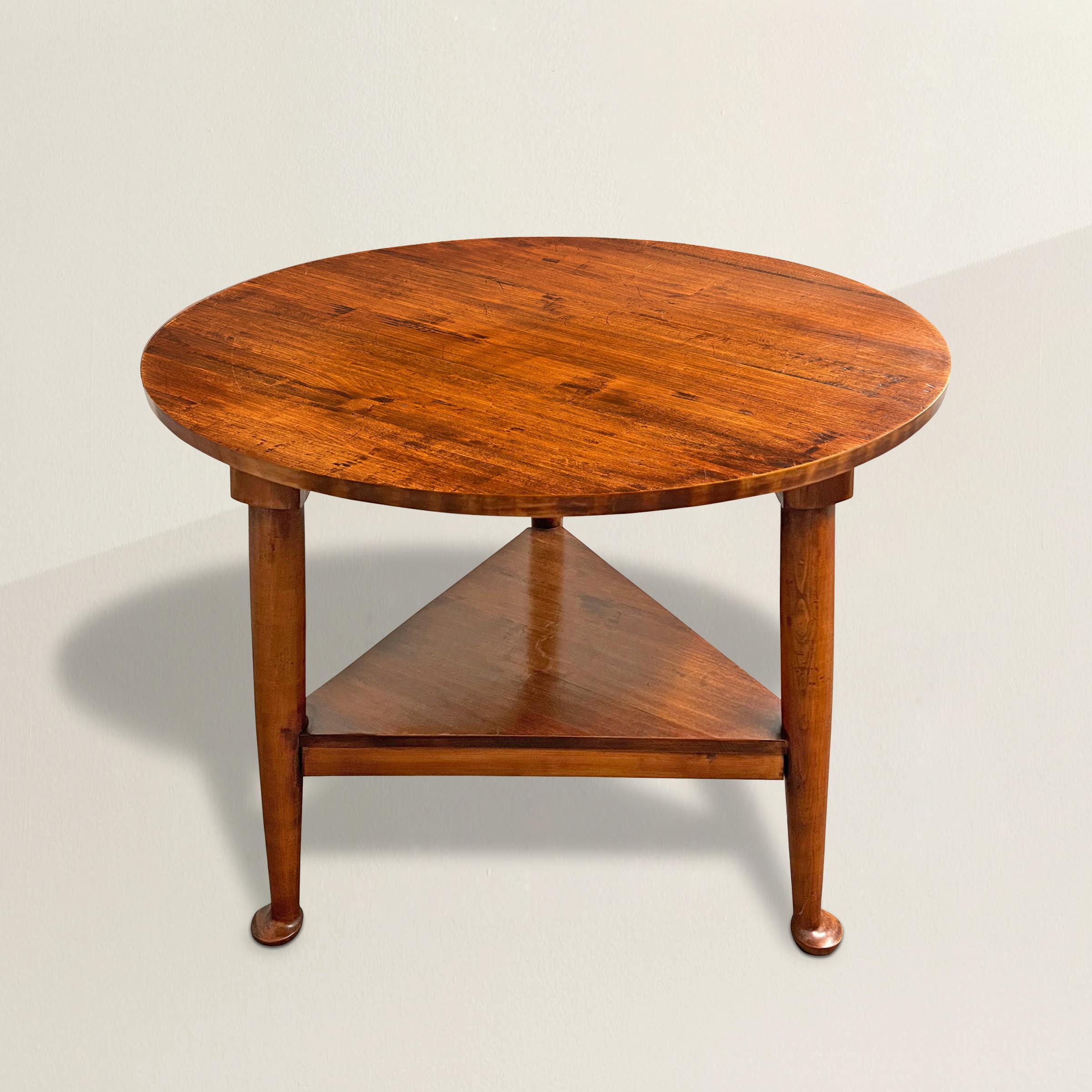 This 20th-century cricket table is a testament to the enduring charm and practicality of this classic design. Featuring a round top, this table's three gracefully tapered legs are not only aesthetically pleasing but also serve a crucial purpose. In
