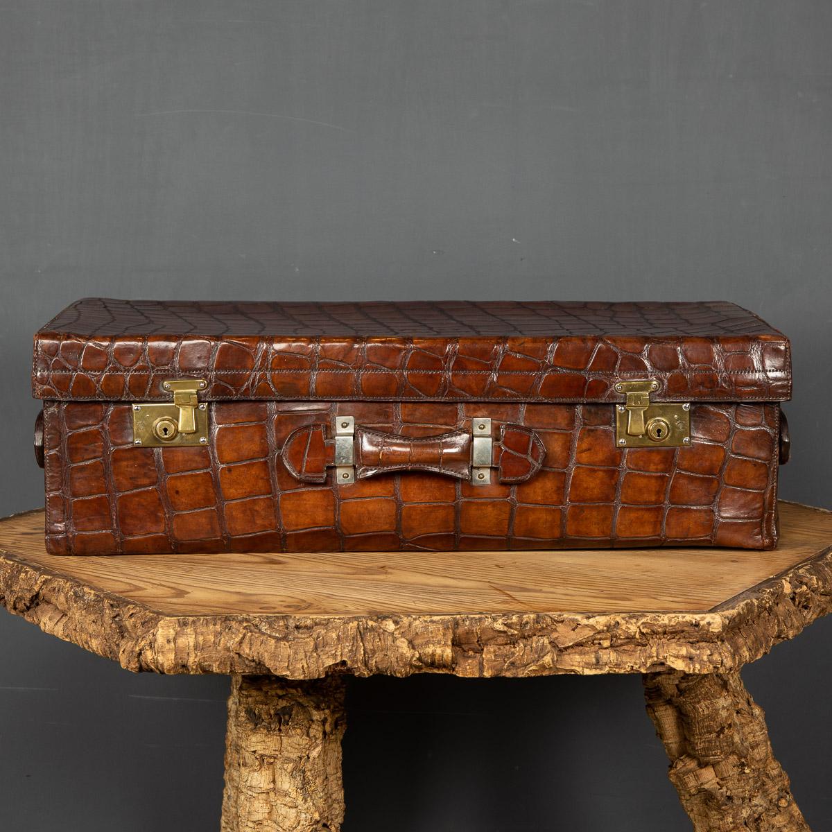 Antique early-20th Century English dark tan crocodile leather suit case. This case has been relined in navy suede. The case is oozing style and elegance, this case makes for a fantastic conversation piece, a very practical item suitable for any