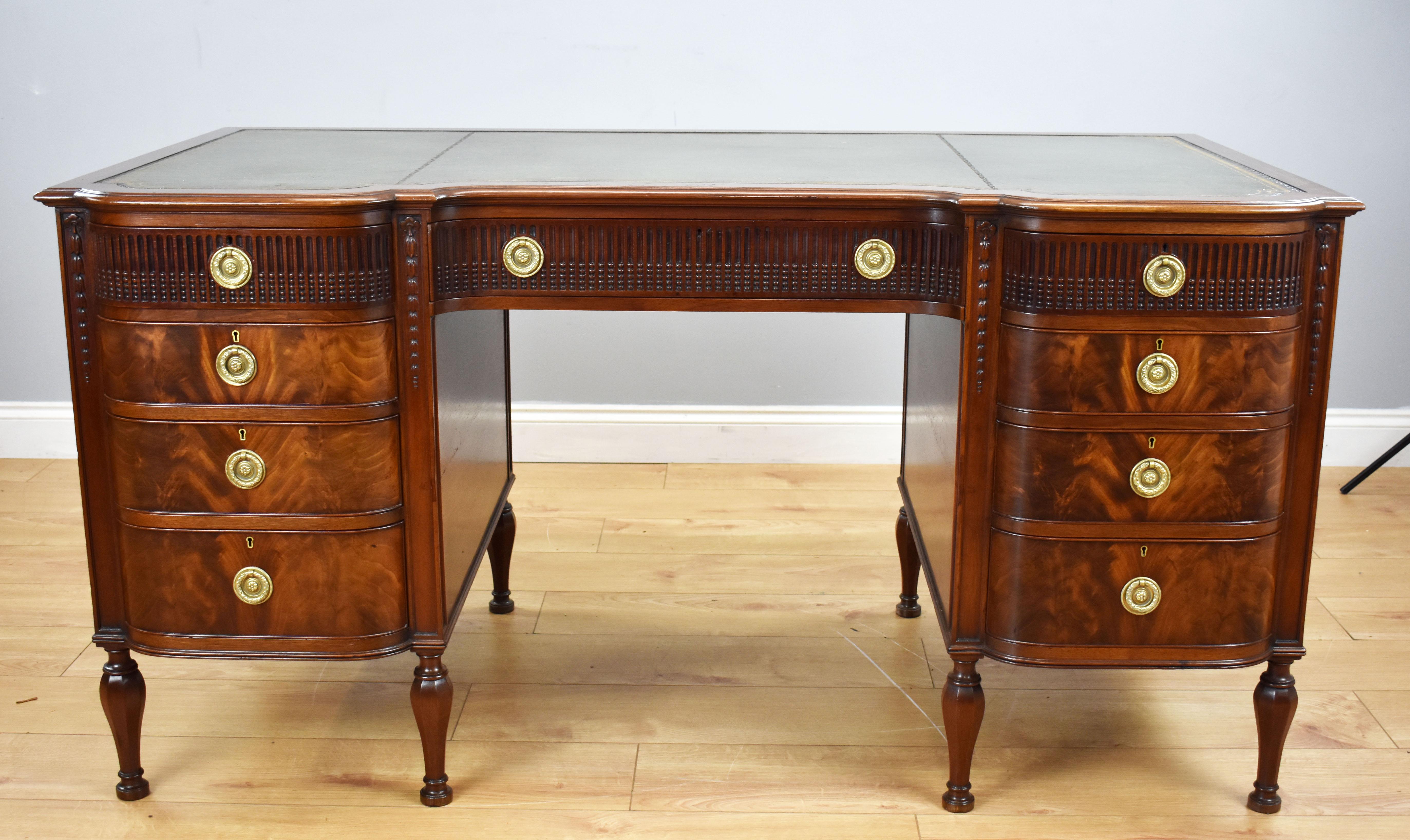 A good quality Edwardian flame mahogany writing table. Having a shaped green leather top, decorated with gold tooling, above three drawers, each retaining their original brass handles. Below this, there are a further three drawers on each side, all