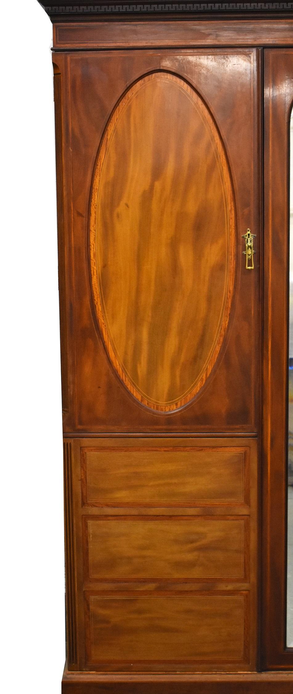 For sale is a good quality Edwardian Triple wardrobe. The top of the wardrobe has a removable pediment with dentil molding. Below the top the wardrobe has three doors, one mirrored door in the centre and one paneled door on either side. When opened