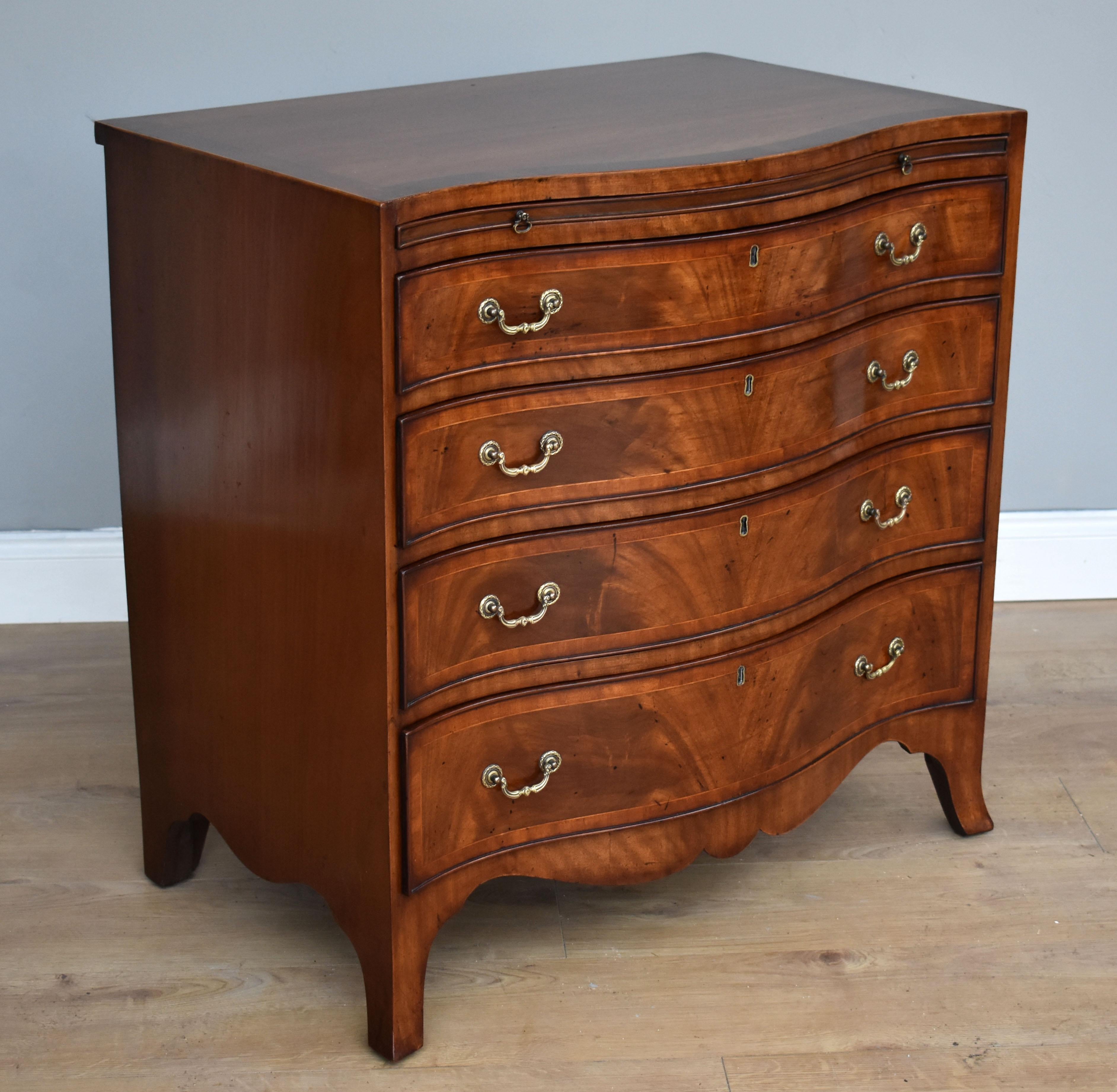 For sale is a good quality Georgian style mahogany serpentine chest. The chest has a brushing slide with two brass pulls, above an arrangement of four graduated drawers, each with brass handles. The chest is raised on splay feet and is in good