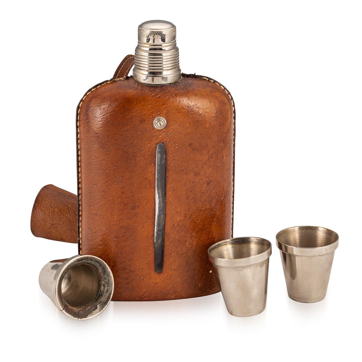 An attractive pair of hip flasks made in the early part of the 20th century. The graduated pair of glass flasks are clad in pig skin leather and two alloy cups are fastened down with a leather strap. Presented in very good condition, the charm,