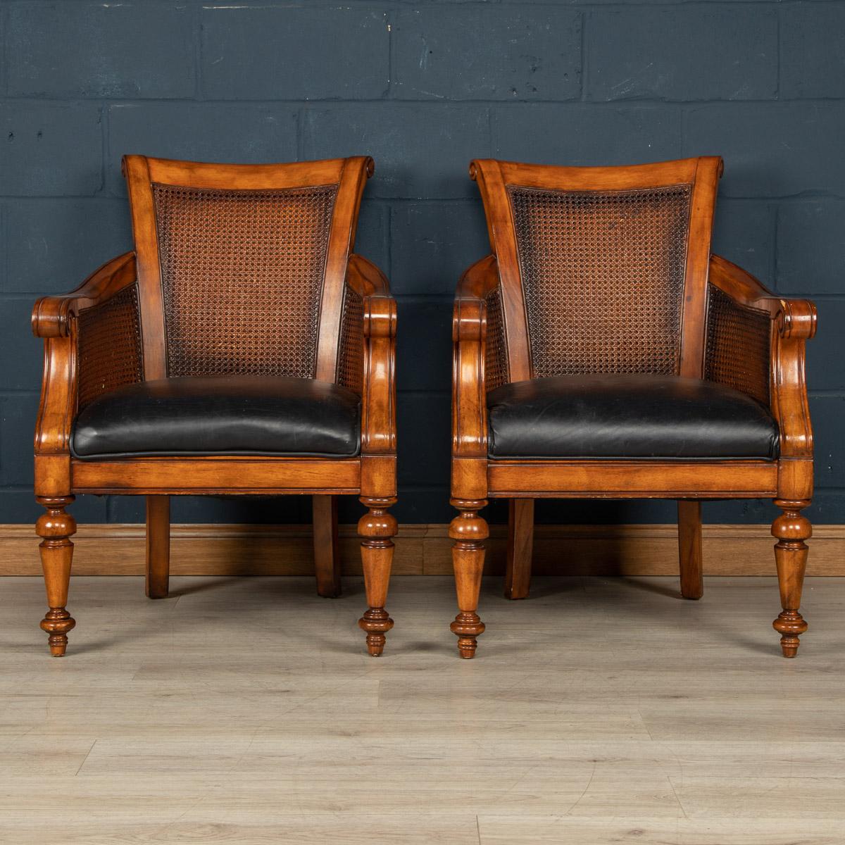 A very elegant pair of armchairs, with a varnished hardwood frame (probably oak or beech), padded leather seating and rattan rear and side panels. A lovely item of furniture manufactured in the classical manner, they are a striking and imposing pair