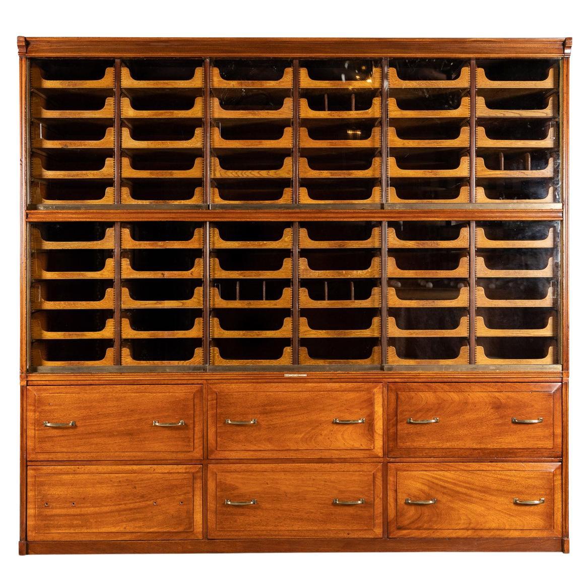 Antique early-20th century English hand crafted mahogany haberdashery, this piece has sixty small open drawers protected by sliding glass doors on ball baring bronze runners. It also has six deep drawers below with original brass fittings. Made by
