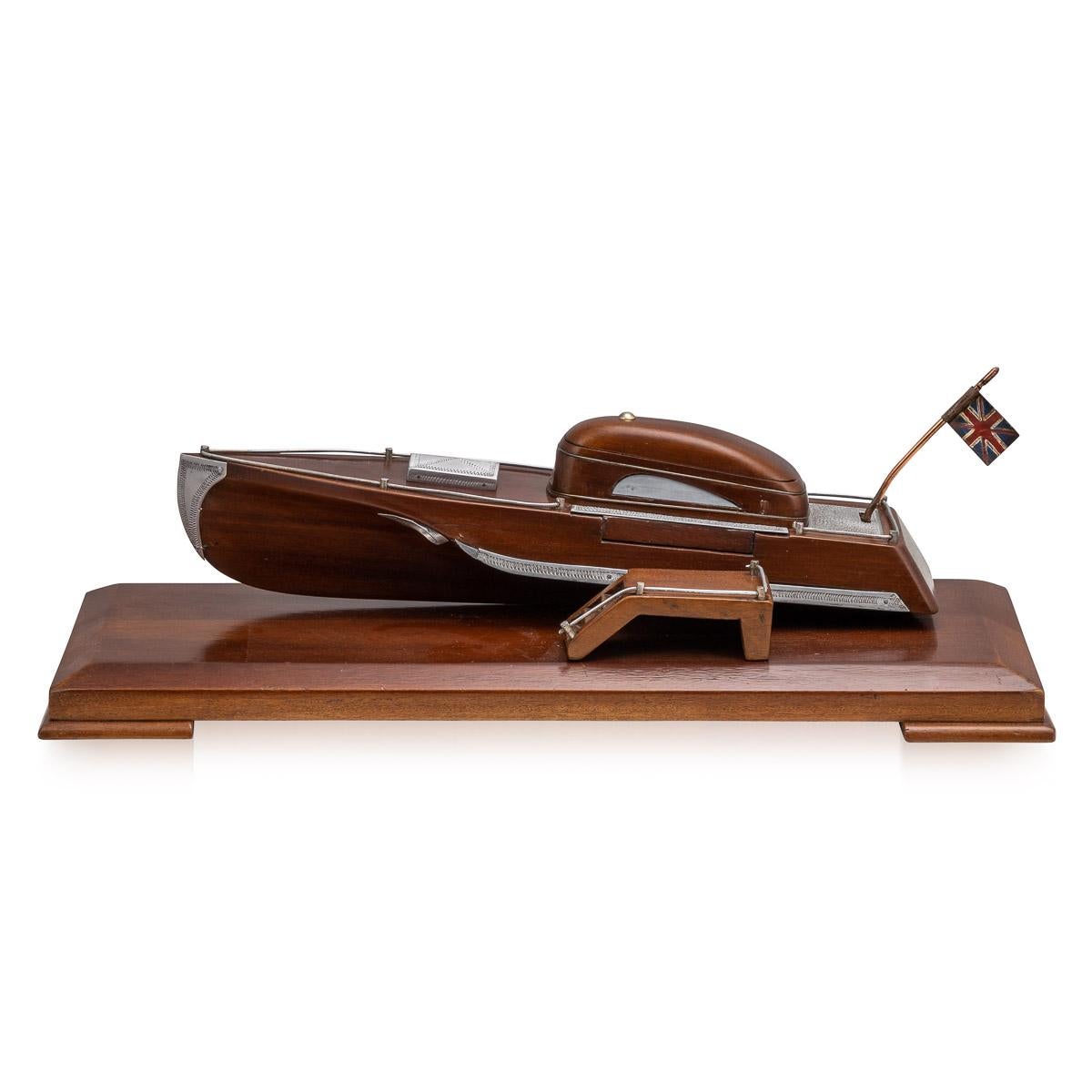 Antique 20th century English mahogany novelty cigarette dispenser, in the form of a motor speed boat, cleverly dispenses the cigarette by pushing the Union Jack flag, a platform for the cigarette to fall on to, in the form of a boarding step,
