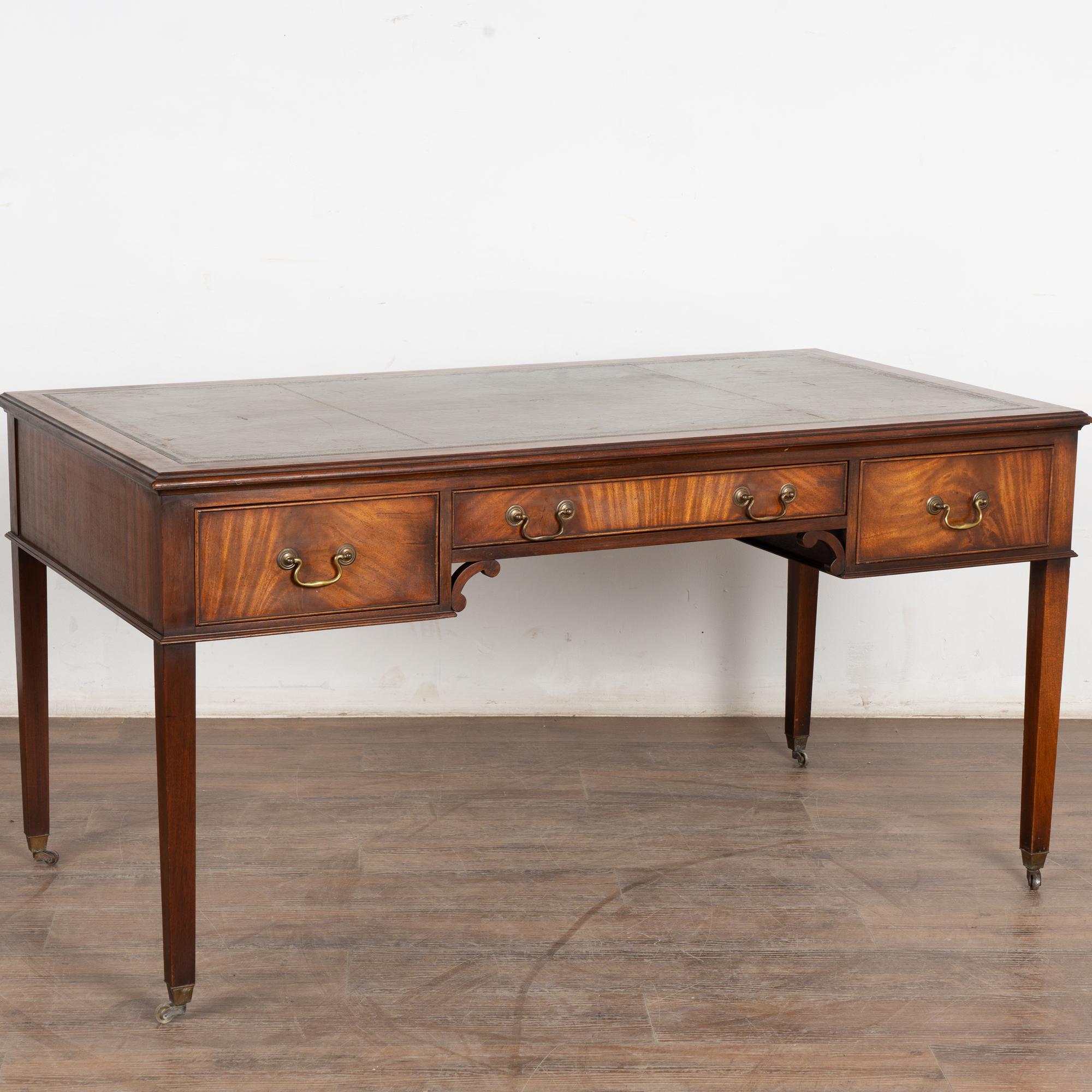 Distinctive and timeless, this English mahogany writing desk has three functioning drawers in the front, and three matching false front (non functioning) drawers on the opposite side.
Note the attractive rich mahogany grain, slender legs resting on