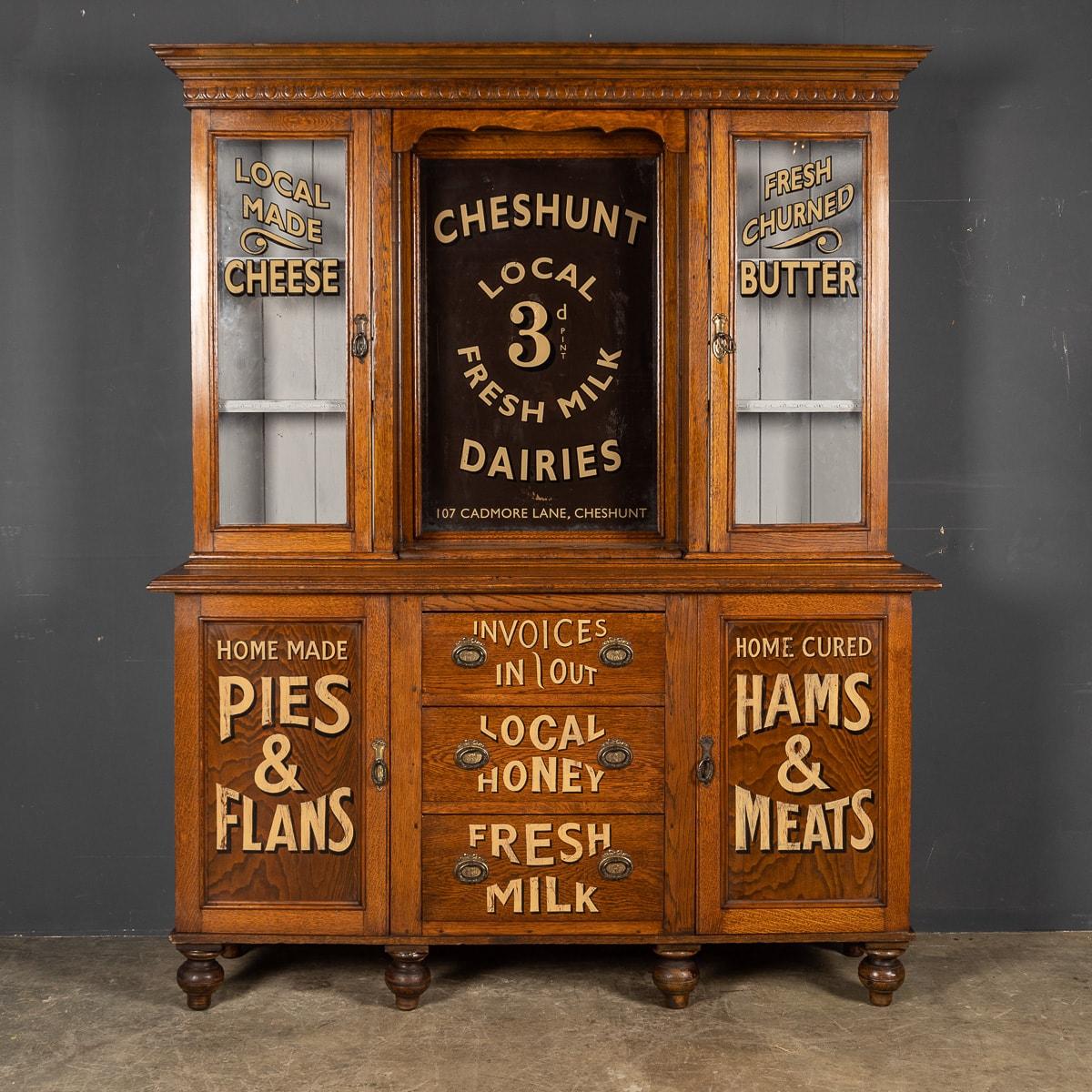 Antique early 20th century English oak dresser, later painted to advertise the wares of a local dairy / grocery shop. This piece set with a central mirror and glass glazed cupboards on either side. Below, there are drawers and cupboards. A wonderful