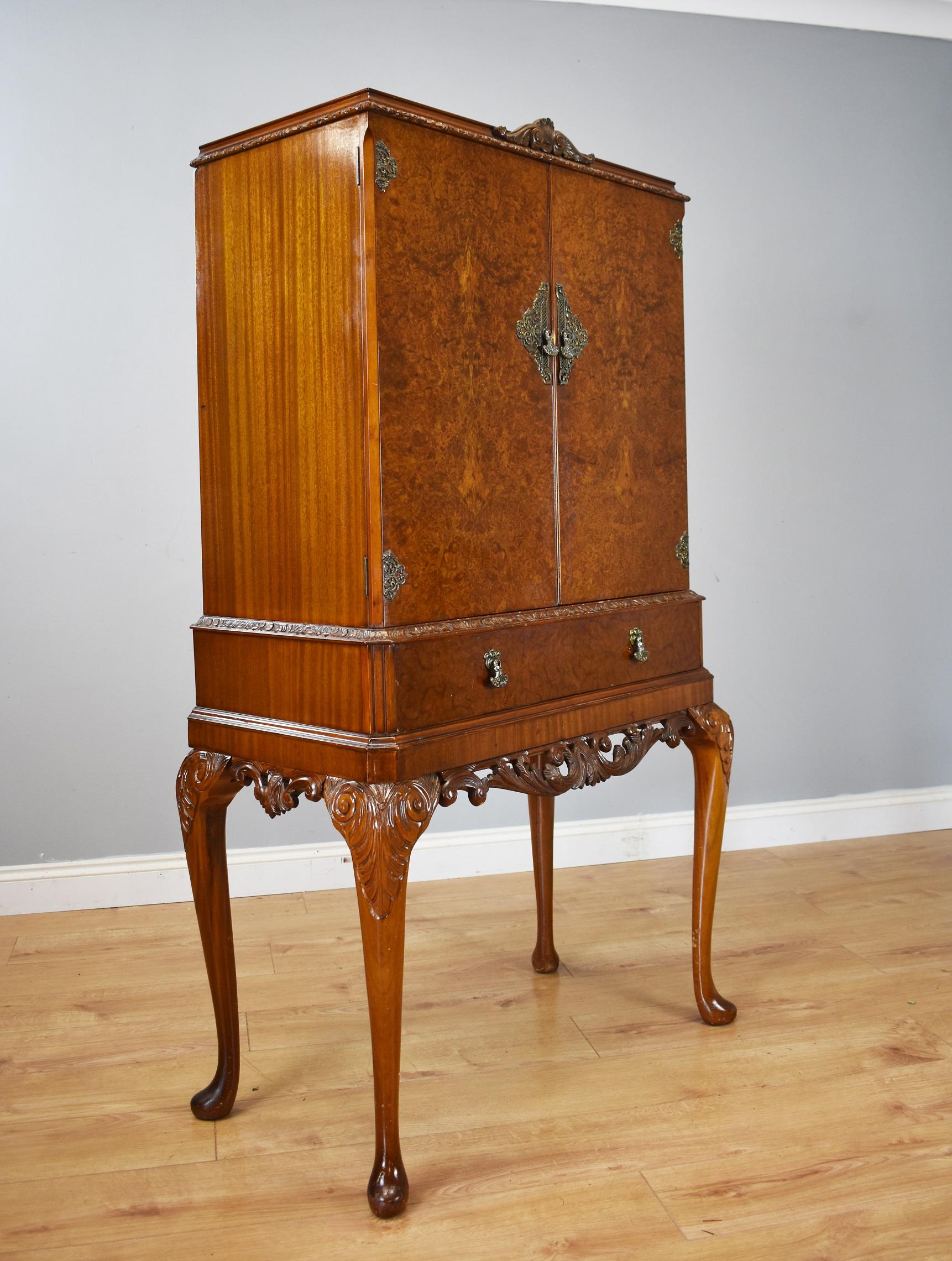 For sale is a good quality 20th century Queen Anne style burr walnut cocktail cabinet, have a carved pediment, above two doors, veneered in beautifully figured walnut, opening to reveal a mirror backed interior, with a single glass shelf. Below this