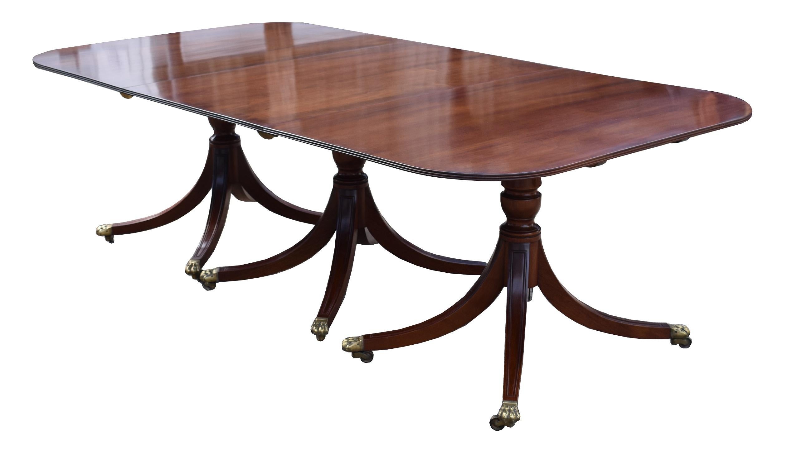 For sale is a good quality solid mahogany Regency style four pillar dining table, complete with three additional leaves. The table is supported by four pedestal bases, each with a turned stem on elegant splayed legs terminating on brass castors. The