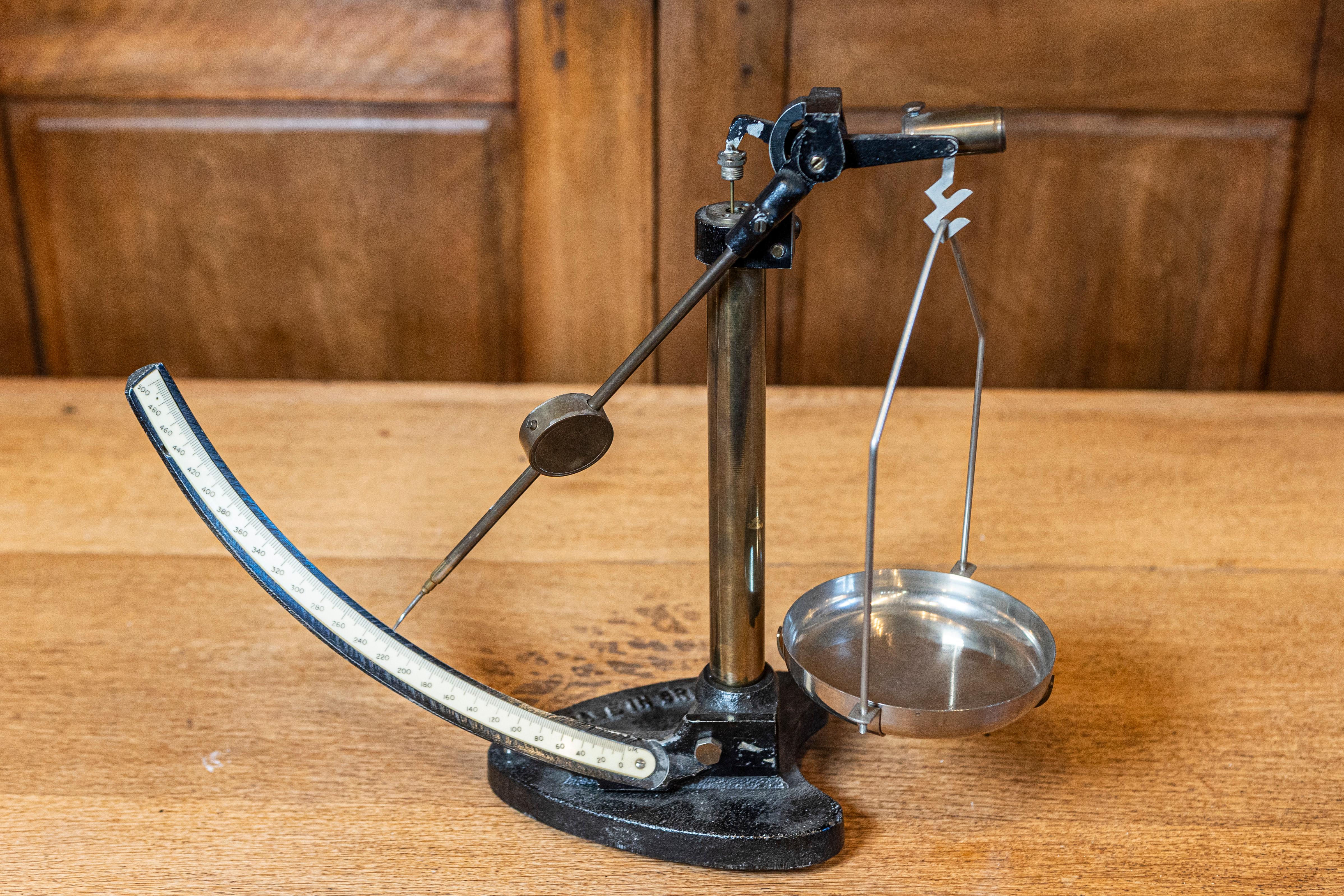 Cette balance anglaise du XXe siècle est une pièce captivante de design industriel et d'histoire fonctionnelle. Fabriquée en fonte avec une base robuste et une poutre en laiton, cette balance incarne la durabilité et l'élégance. Le mécanisme