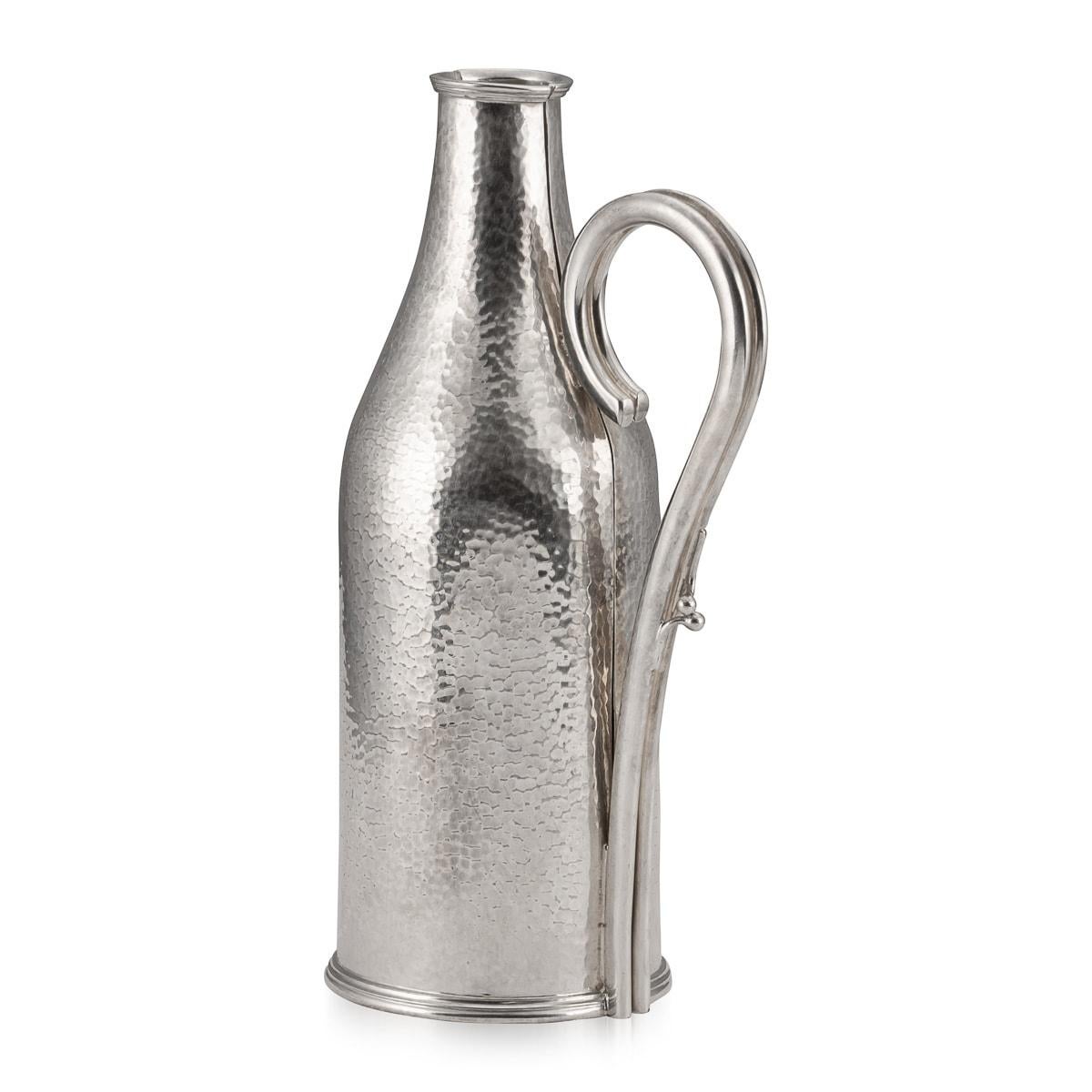 Un joli porte-bouteille en métal argenté, fabriqué dans la première moitié du XXe siècle en Angleterre et vendu par le célèbre joaillier Mappin and Webb. Il est conçu pour abriter une bouteille ayant la forme d'un champagne ou d'un prosecco moderne