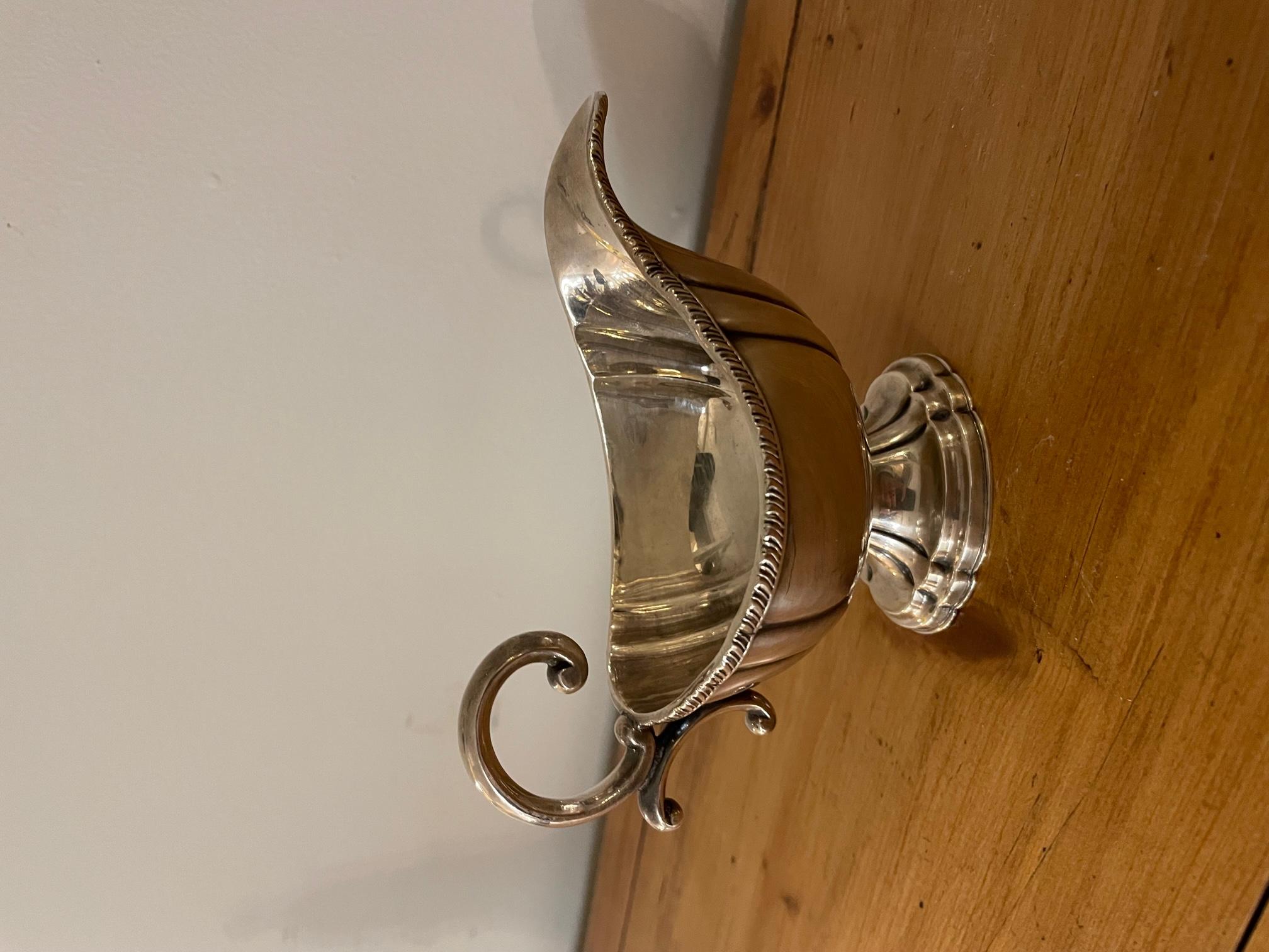 Very nice and elegant silver plate gravy boat with beautiful details all around the top and with a nice handle. 
At the back we can see 