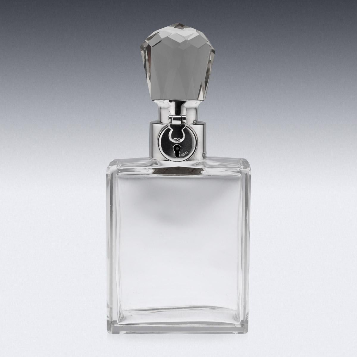 20th century English Art Deco silver & glass spirit decanter. Of mid size with glass body and mounted with elegant octagonal cut stopper. Applied with a silver collar and lock mechanism with key. Hallmarked English silver (925 standard), London,