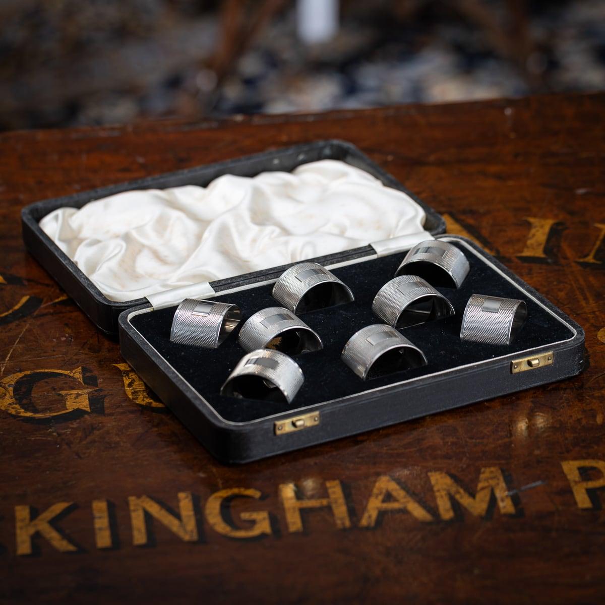 Vintage 20th Century English solid silver cased set of eight napkin rings. L'ensemble est livré avec son étui en cuir d'origine. Chaque rond de serviette a été guilloché sur l'ensemble du corps avec une petite zone pour graver des initiales ou un