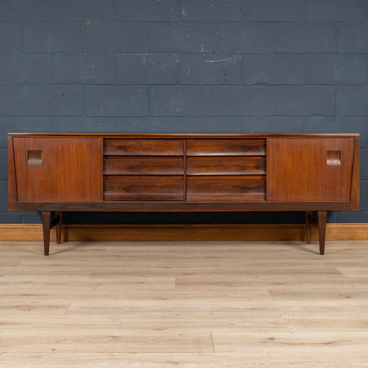 A wonderful and very rare mid century sideboard, made in England around the 1960s. The rarity is in the detail and it shows British cabinetmaking at its finest and most adventurous. The sideboard is made out of two types of wood: Brazilian rosewood