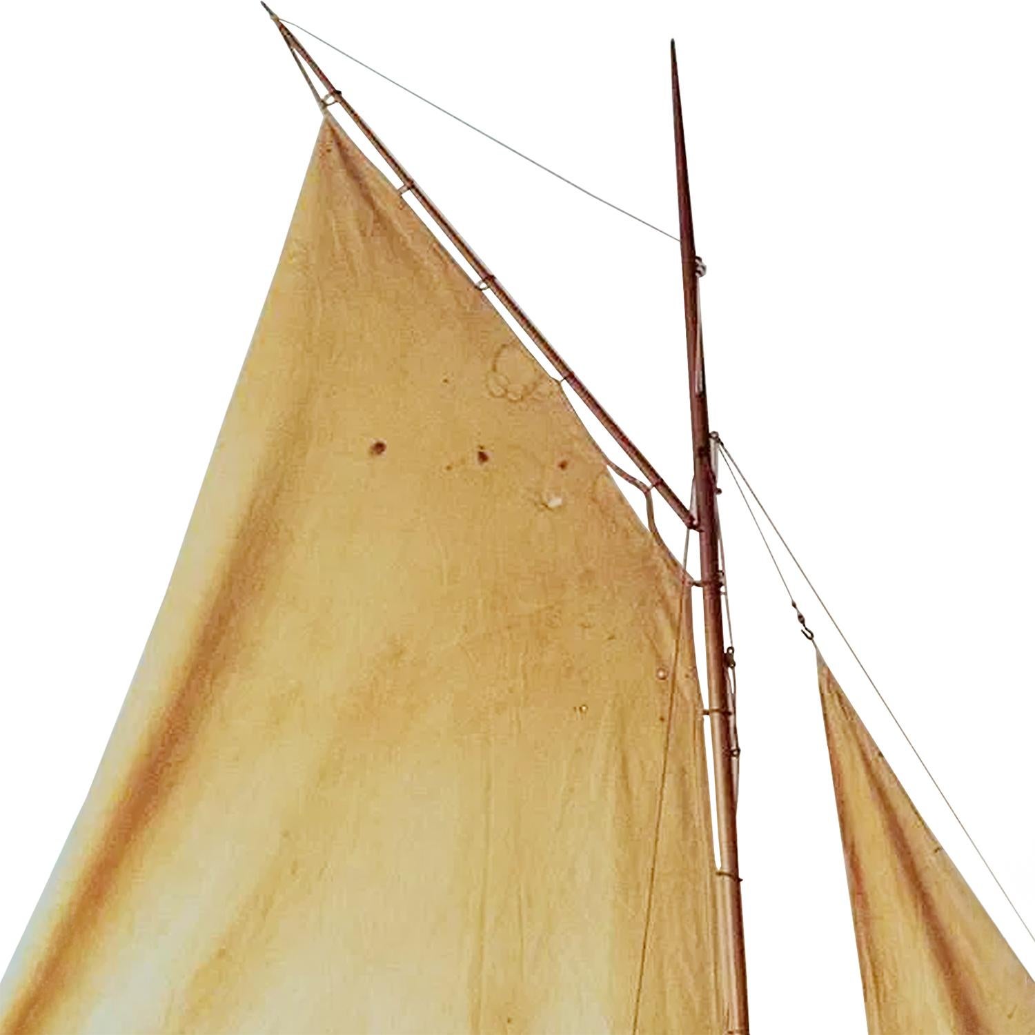 A sculptural, antique preserved European Art Deco pond yacht model, hand crafted from polished Pinewood and dating to the early 20th Century, in good condition. This sailboat features two original fabric sails, gracefully mounted and enhanced with