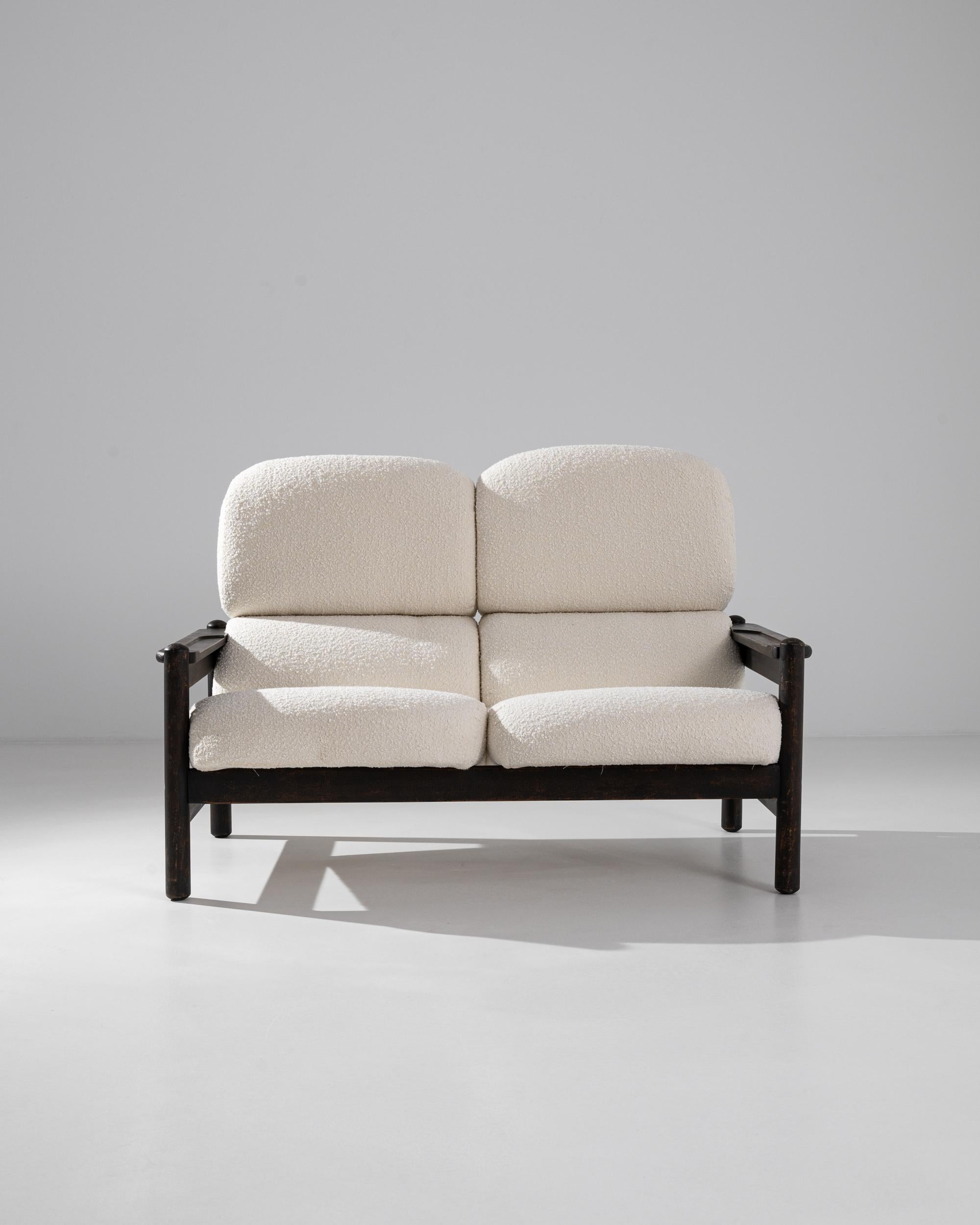 This vintage loveseat offers a flawless balance of sophistication and comfort. Made in Europe, the design is both graphic and relaxed: the clean rectilinear lines of the wooden frame are softened by the rounded ends of the legs; the full cushions of