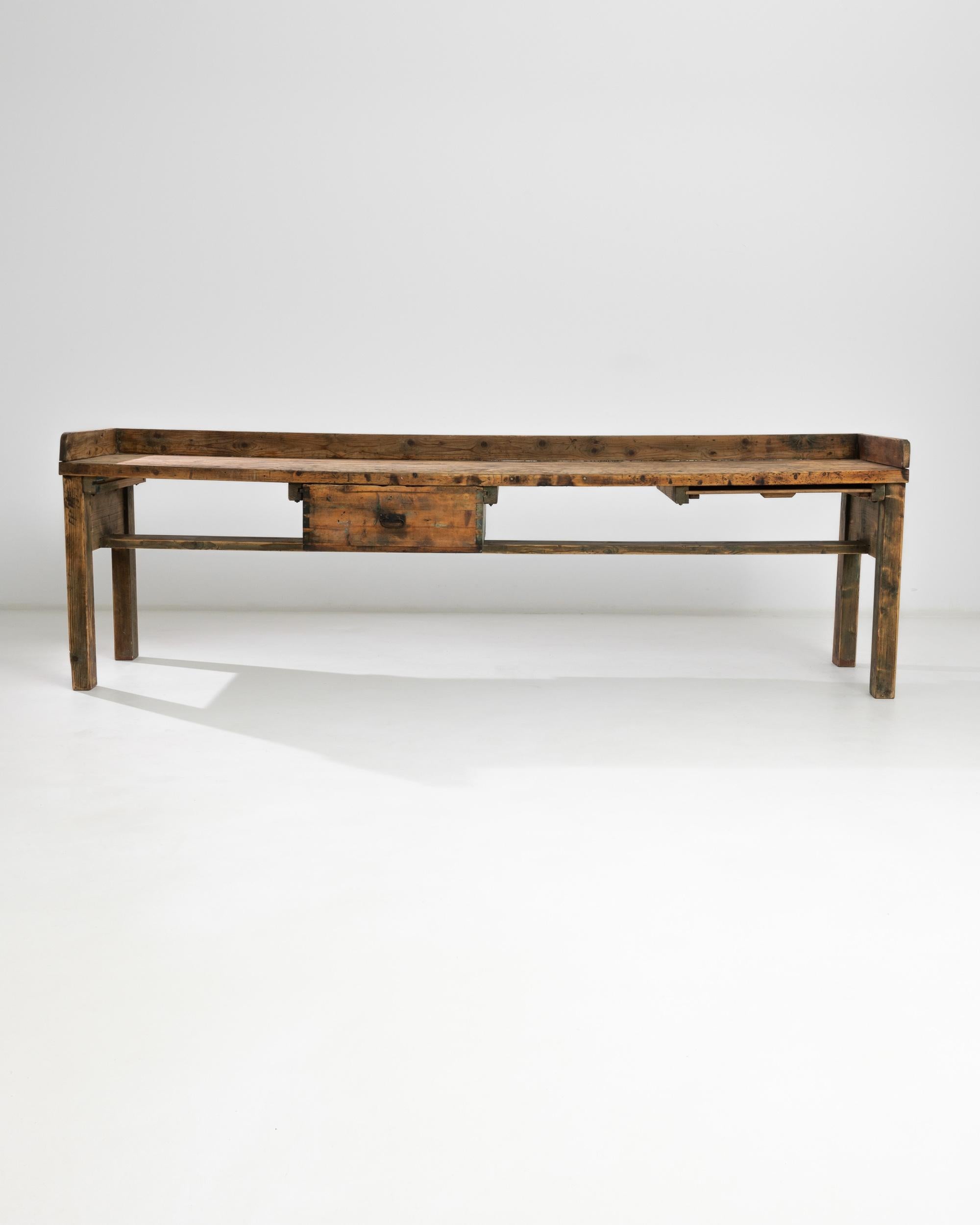 The aged patina of this vintage Industrial work table gives the robust Silhouette a warm glow. Made in Central Europe in the 20th century, the long tabletop sits atop a simple wooden frame; a wooden surround prevents items from being accidentally