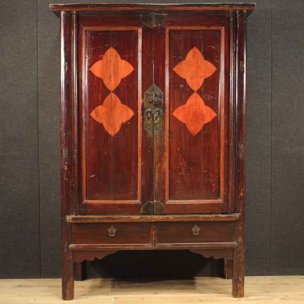 Chinese wardrobe from the mid-20th century. Furniture carved in exotic wood of great size and impact. Two-door wardrobe equipped with two external drawers of excellent capacity and service. Interior complete with two shelves and two drawers.