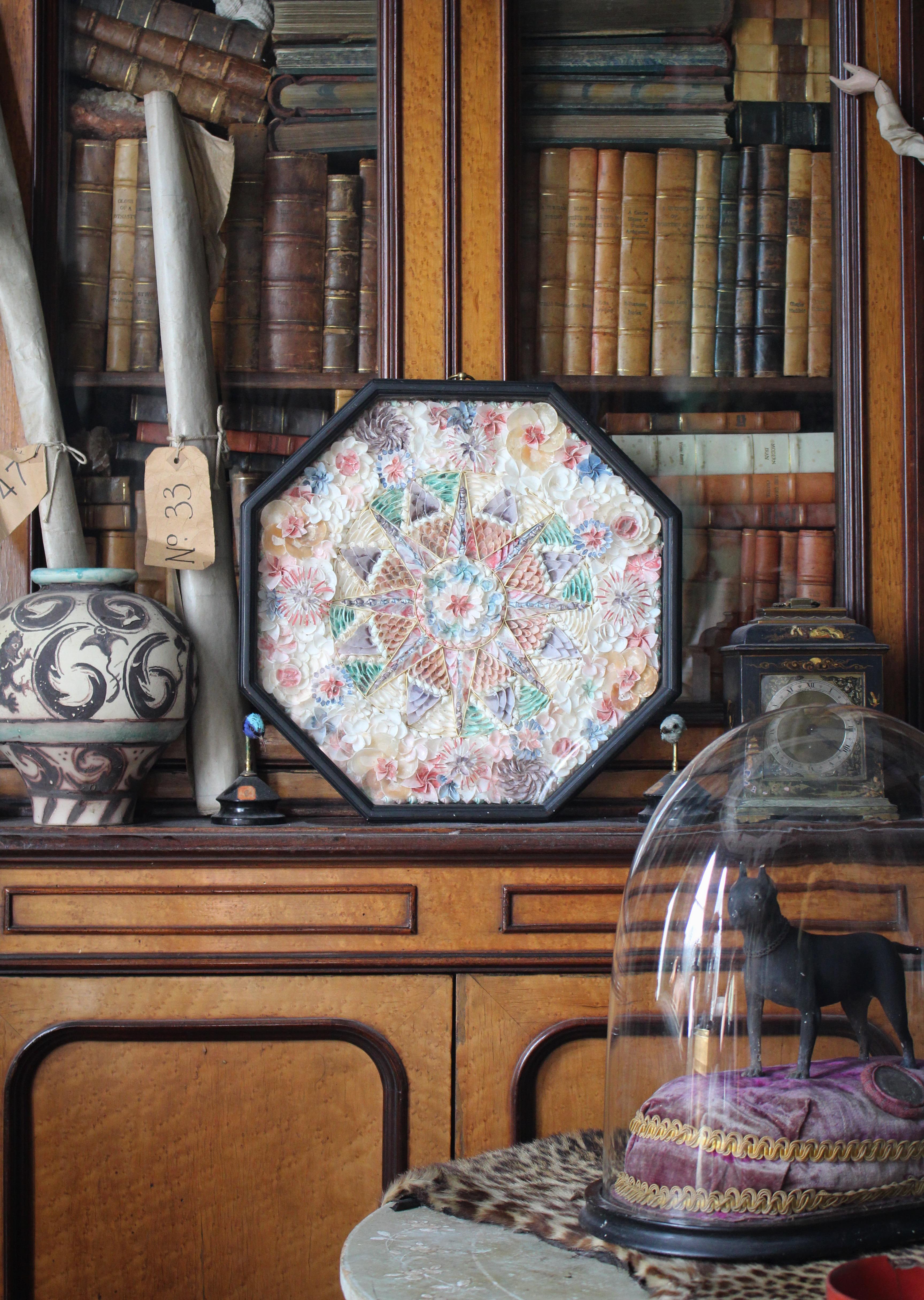 An extra large shellwork display/panel, worked in a variety of specimens, heightened with watercolour and arranged with a star to the centre surrounded by floral blooms, housed in an octagonal, glazed and ebonised frame.

Very much in the manner of