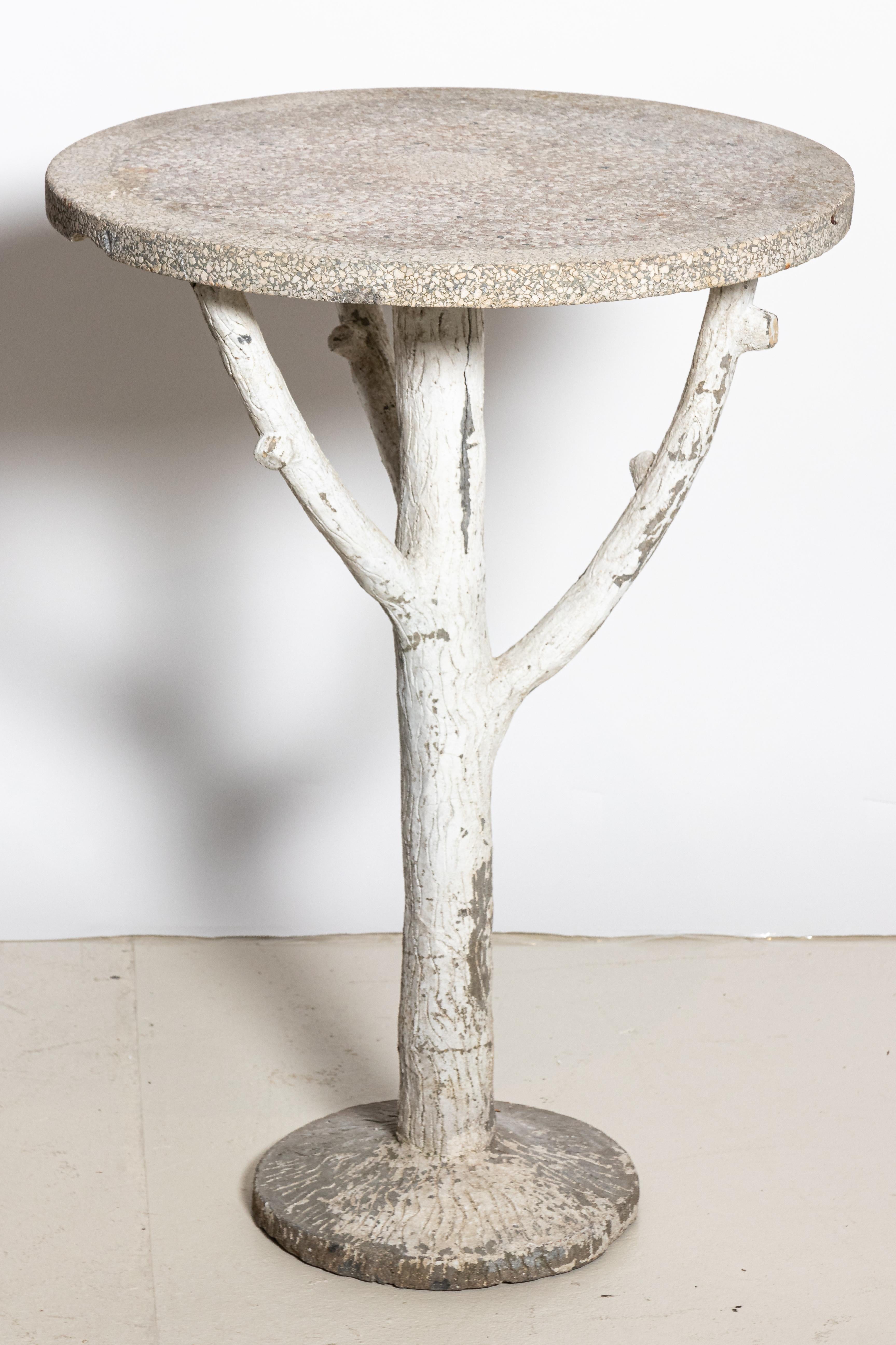 Rustic cast stone garden table with white painted faux bois base, made in England circa early 1900s. Textured cast stone tabletop is supported by a sturdy base of rough-hewn branches. Tall with a petite round top, this occasional table is a nice