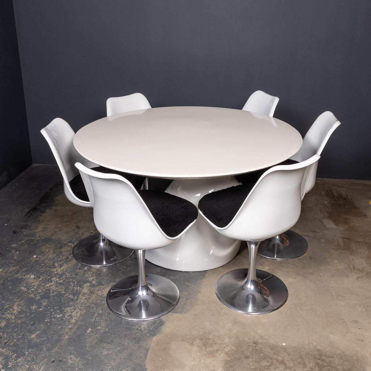Modern mid-20th Century white lacquered fiberglass table on a large asymmetrical pedestal accompanied by a set of six complimentary Tulip swivel chairs in white lacquered fiberglass with an aluminum base and a contrasting, black shearling
