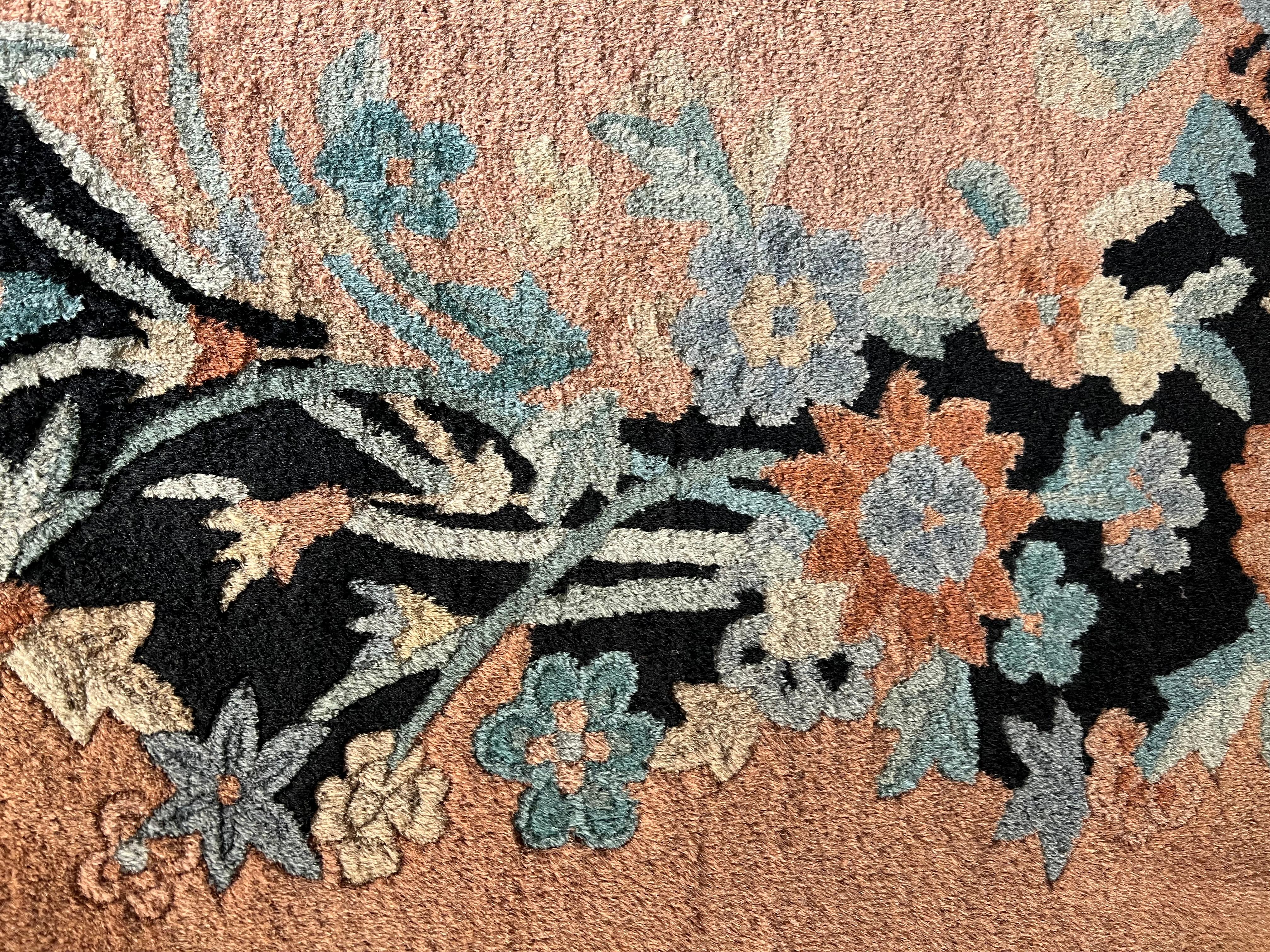 From the unusual style is recognized this beautiful Chinese carpet of the Art Deco period in bright colors and rather unusual. On the salmon pink background there is a cascade of flowers with shades ranging from green to blue, from beige to pink and