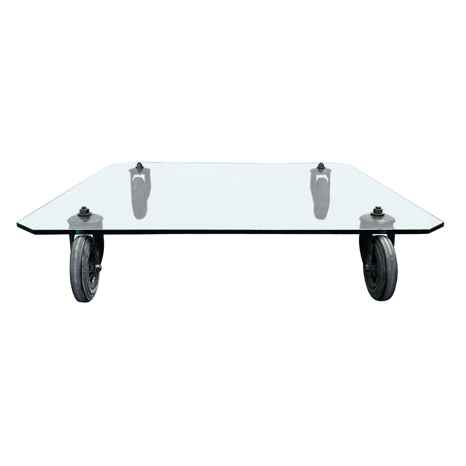 A vintage Mid-Century Modern coffee table ( tavolo con route ) from Gae Aulenti, the original for Fontana Arte, with glass top and swivel wheels in good condition. The Italian industrial trolley was used to transport glass in the Fontana Arte plant.