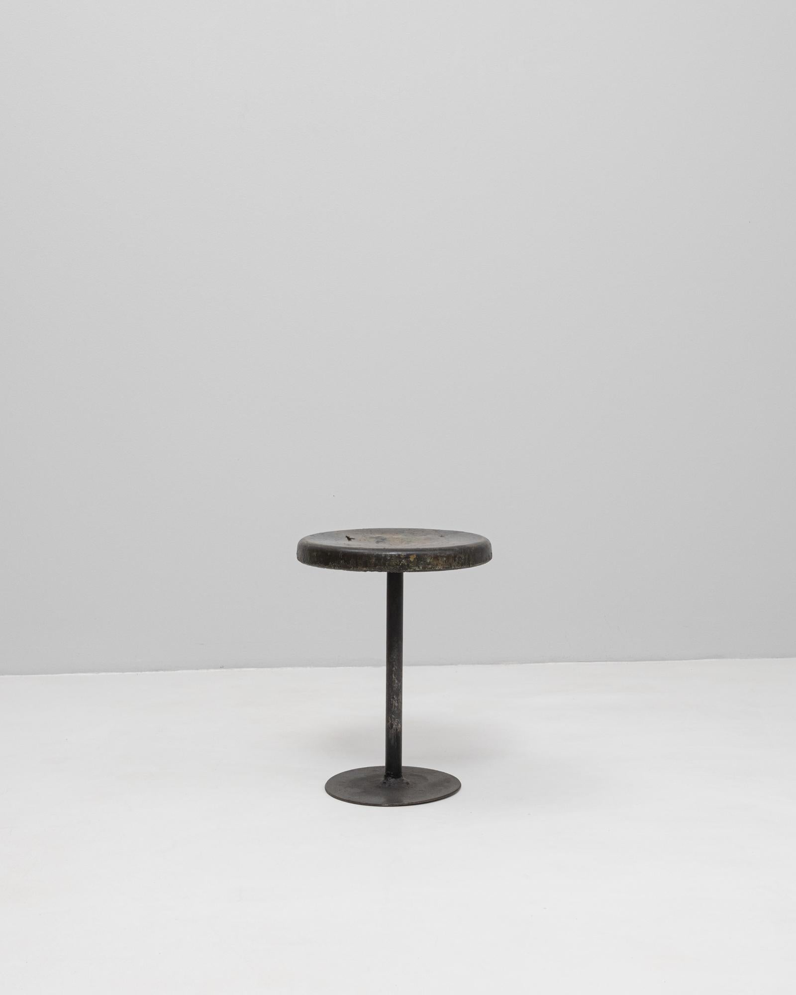 Exemple frappant du début du design industriel, ce tabouret français du XXe siècle présente une silhouette minimaliste combinant une base en métal solide et une assise en bois épaisse et ronde. L'assise présente une patine magnifiquement usée,