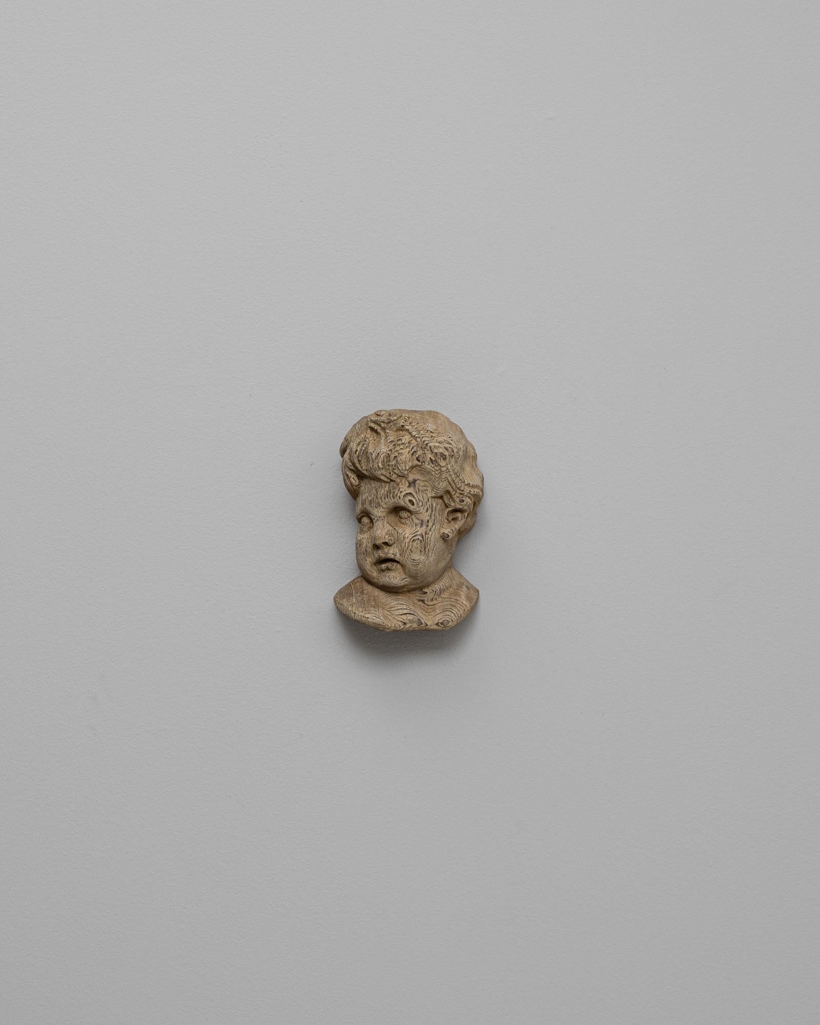 Sculpture murale en chêne français du 20e siècle représentant un bébé. Cette sculpture murale en chêne finement sculptée représente la tête d'un jeune enfant aux traits doux et arrondis et aux cheveux délicatement détaillés. Le grain naturel du
